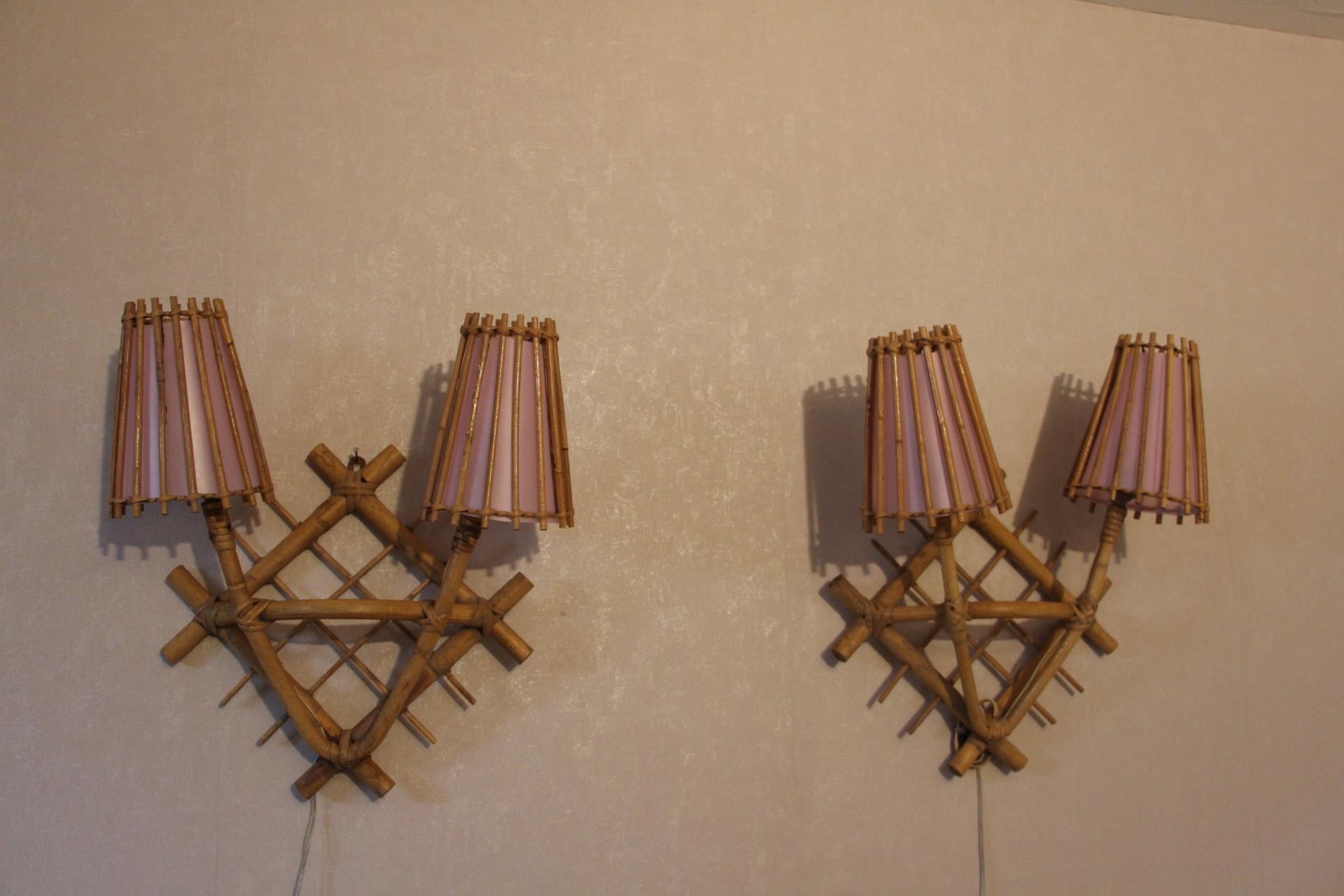 Vintage pair of Louis Sognot rattan sconces from France, 1960s. Rattan torch shape with 2 bulbs in each. Original rattan finish, new interior shade without any markings.
Thanks to their pink lampshade, their light is very soft.