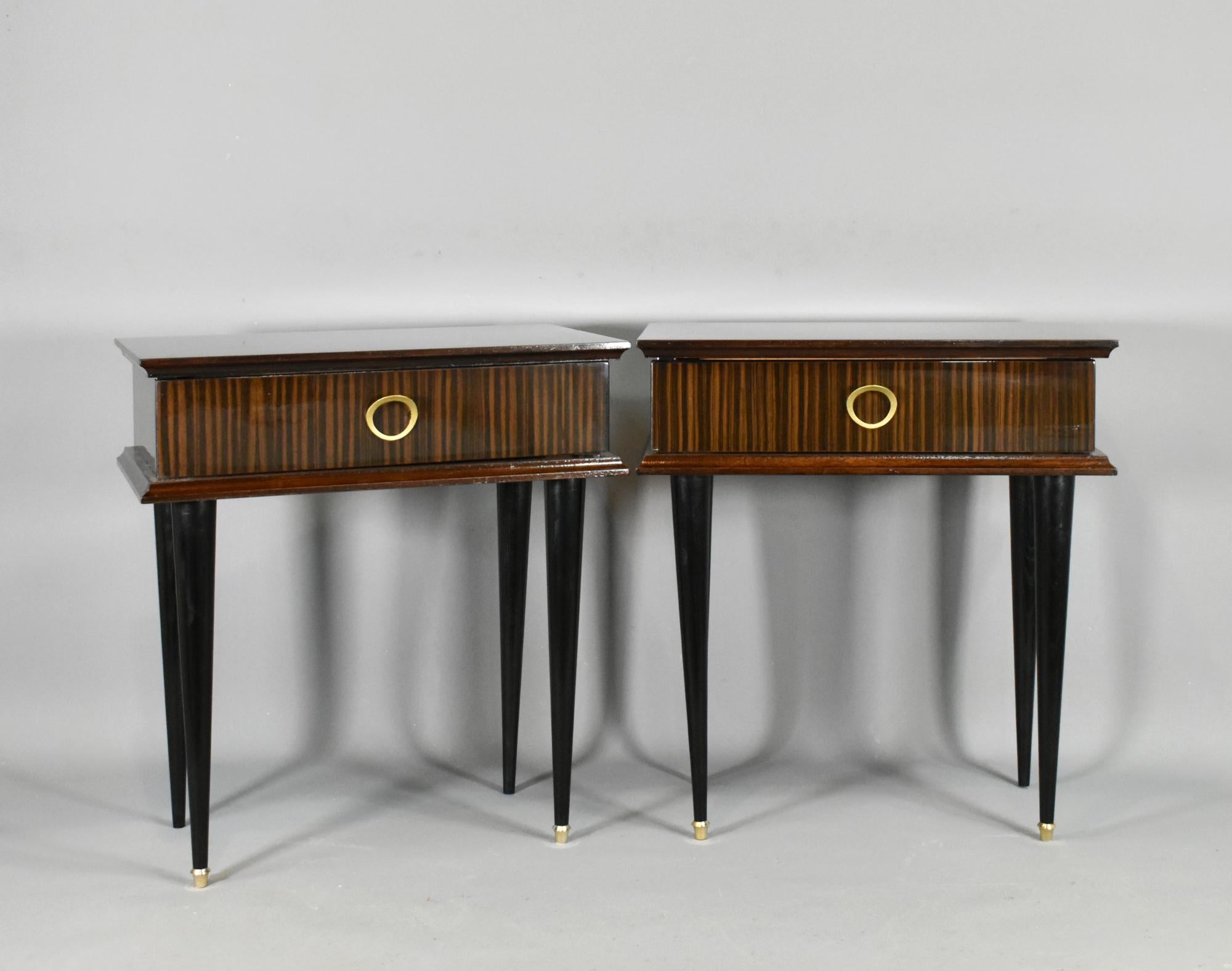 Pair of French 1970s Night Stands in Macassar Ebony 

A pair of matching 1970s Night Stands in Macassar Ebony standing on turned tapered legs with gold-coloured feet to the front legs. 

Both the full-width drawers feature a gilt metal drawer pull