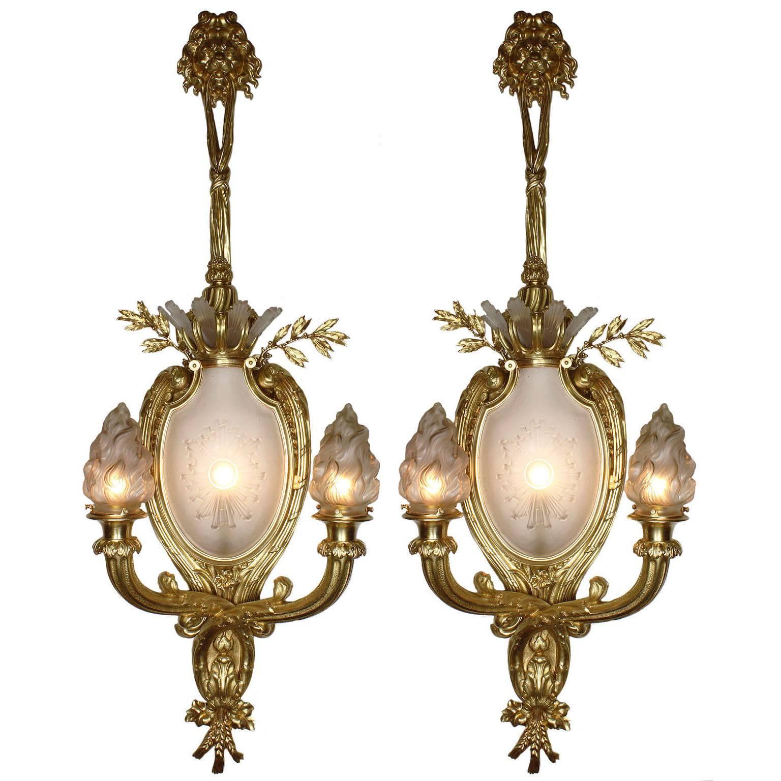 A Palatial pair of French 19th-20th century Louis XV style figural gilt-bronze and frosted molded-glass two-light wall light luminéres. Each sconce centered with an ovoid frosted molded glass plaque edged with a sun-burst design below six frosted