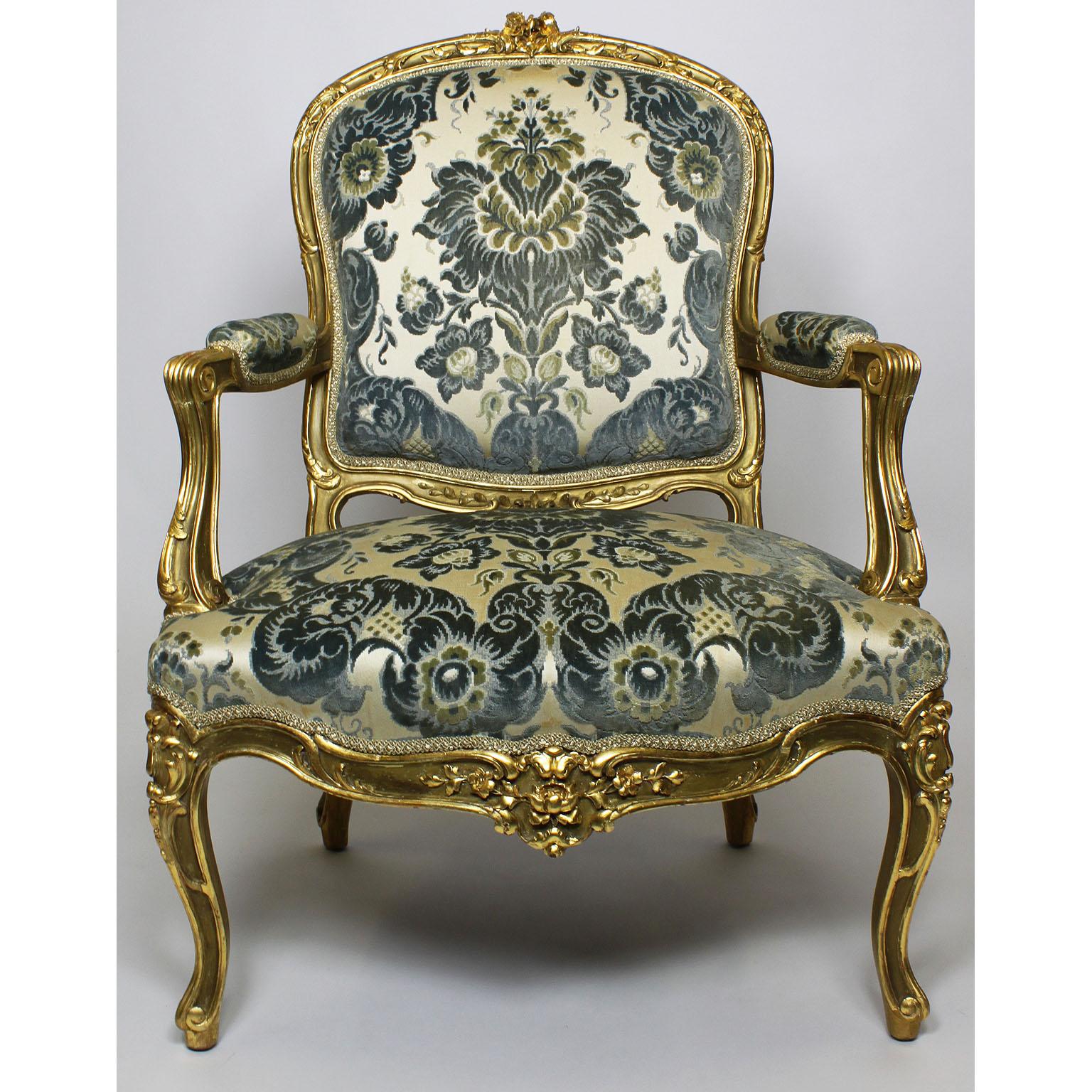 A fine pair of French 19th-20th century Louis XV style two-tone giltwood carved Rococo fauteuils (Armchairs). The intricately carved wood frames with open scrolled and padded armrests and cabriolet legs. Upholstered in a Baroque blue and cream