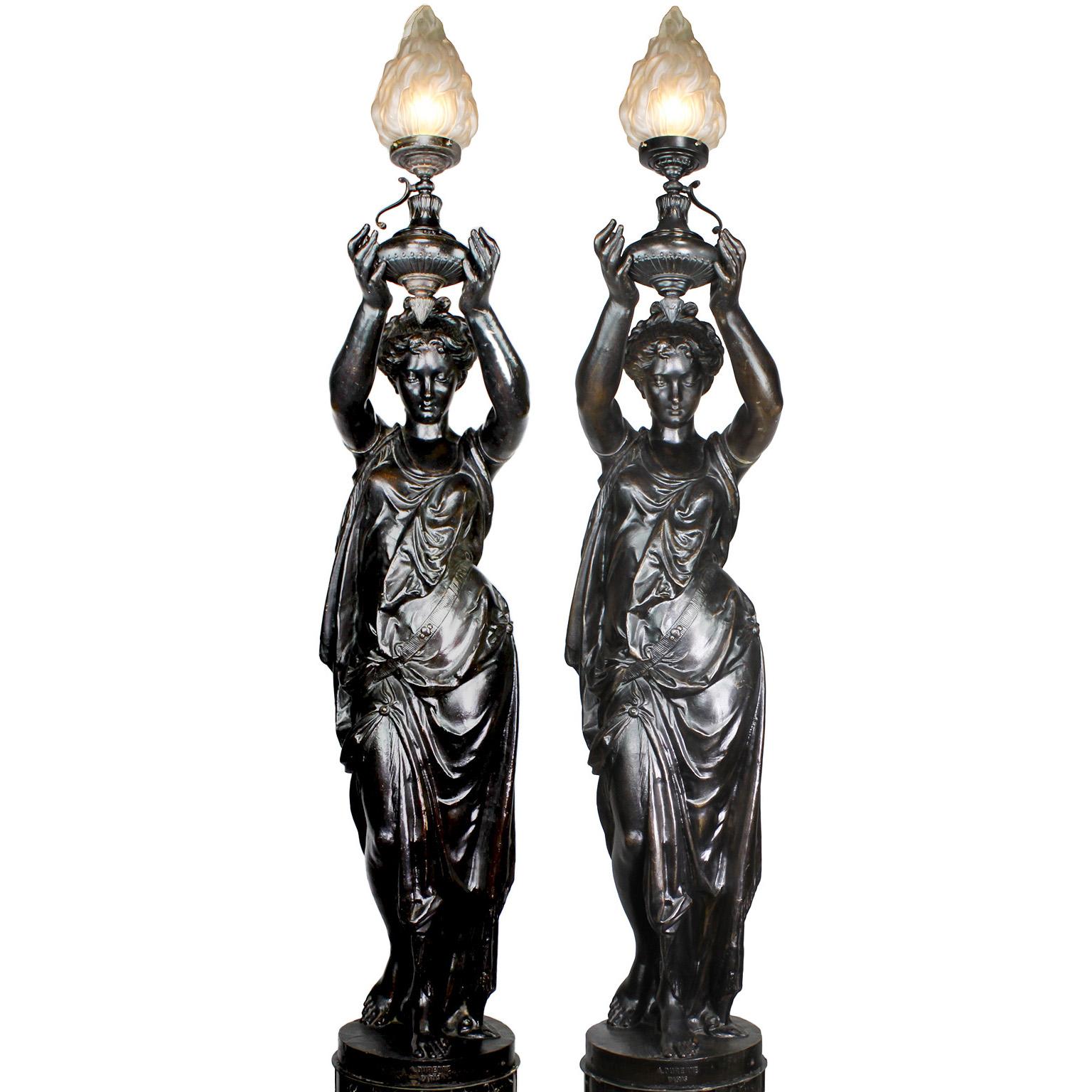 A very fine pair of French 19th-20th century neoclassical style patinated cast iron figural torchères by A. Durenne, Paris, each representing a figure of a standing young maiden, her arms raised forward while holding a a flaming urn gas light (Now