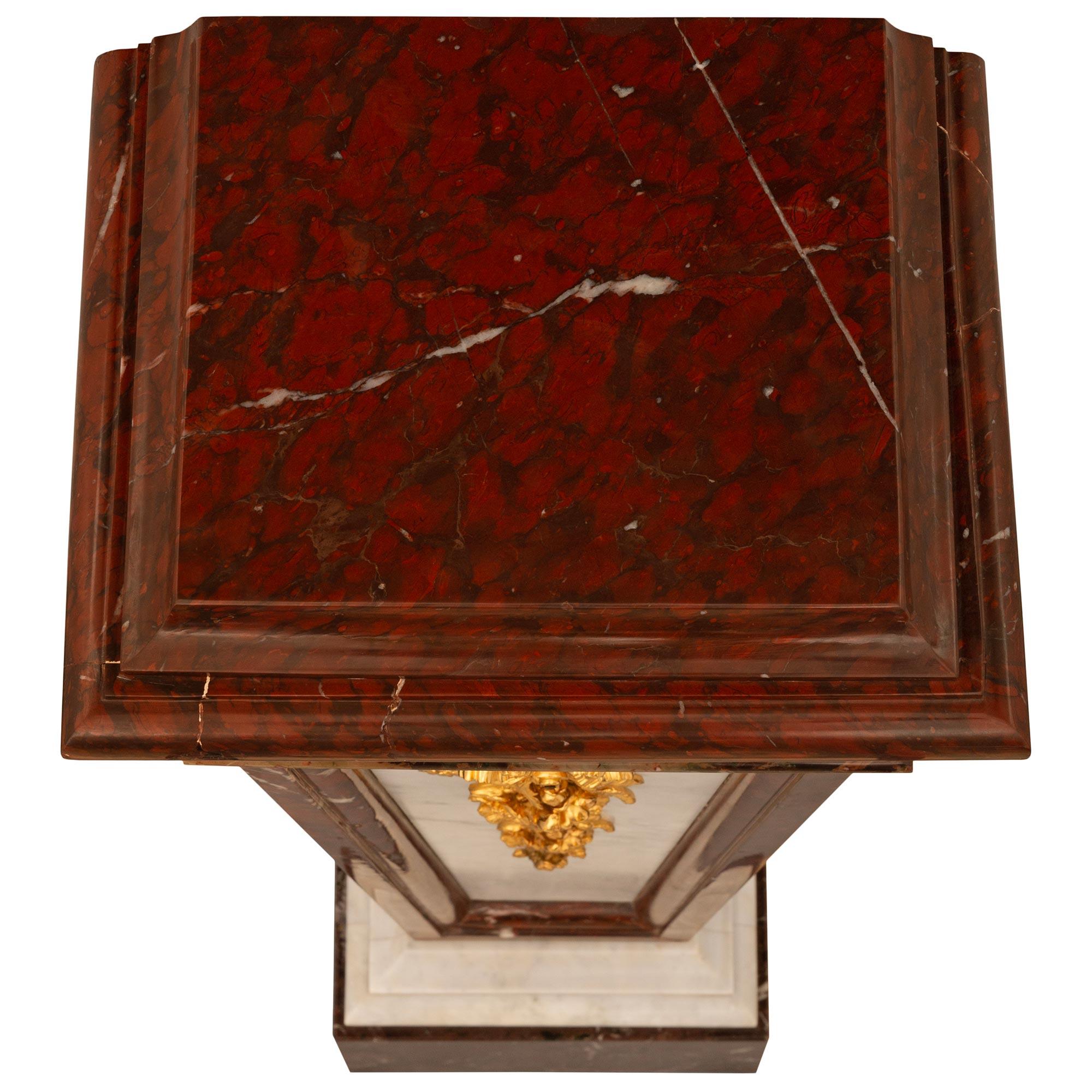 A fine and very elegant pair of French 19th century Louis XVI st. White Carrara, Rouge Griotte, Campan Rubané Marble, and Ormolu pedestals. This lovely and impressive pair of pedestals are raised on square supports made of Rouge Griotte marble below