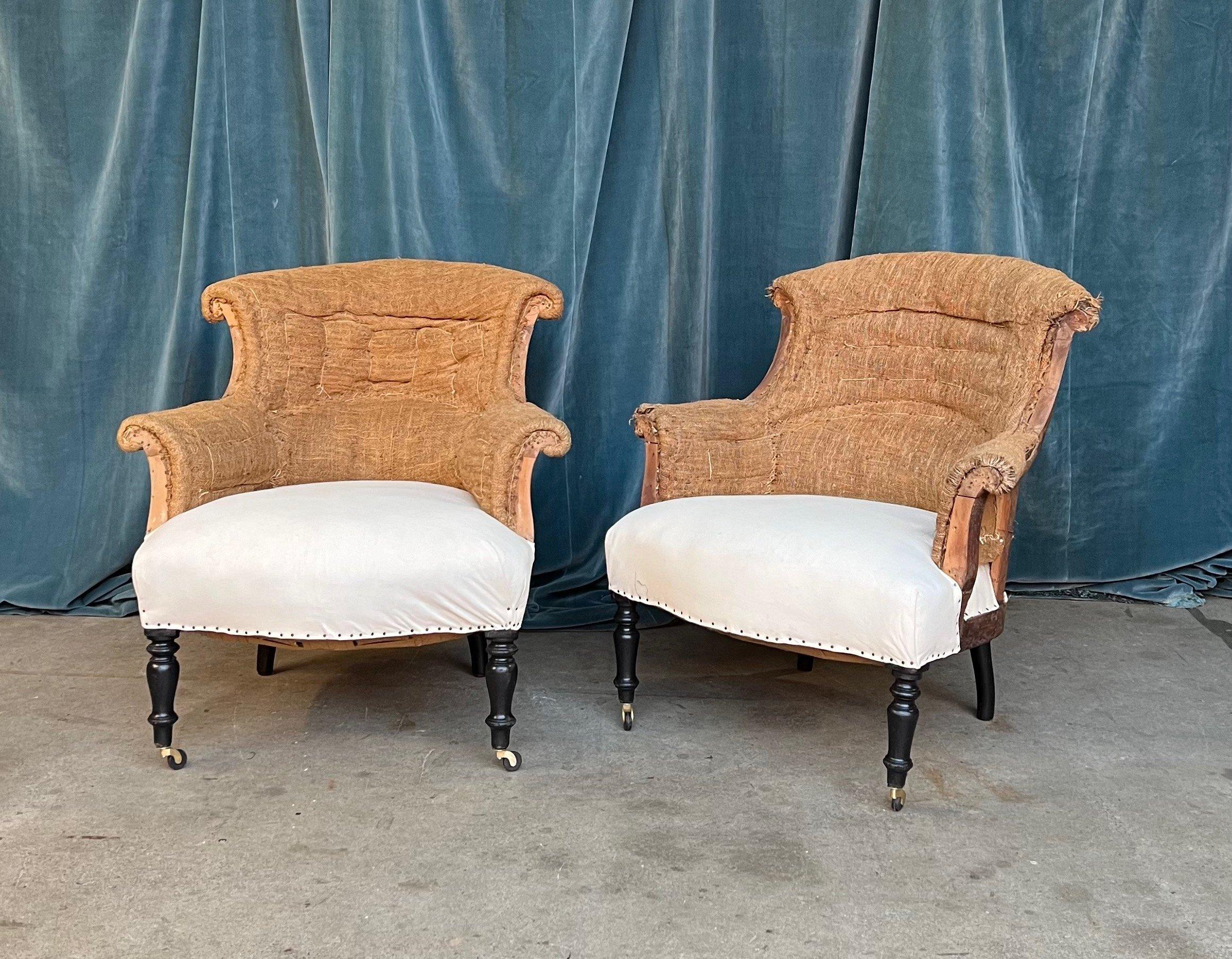 Une paire classique de fauteuils Napoléon III français avec des accoudoirs et un dossier à volutes. Les chaises ont été déshabillées jusqu'à la toile de jute et la mousseline et sont prêtes à être tapissées. Nous avons ajouté des roulettes aux pieds