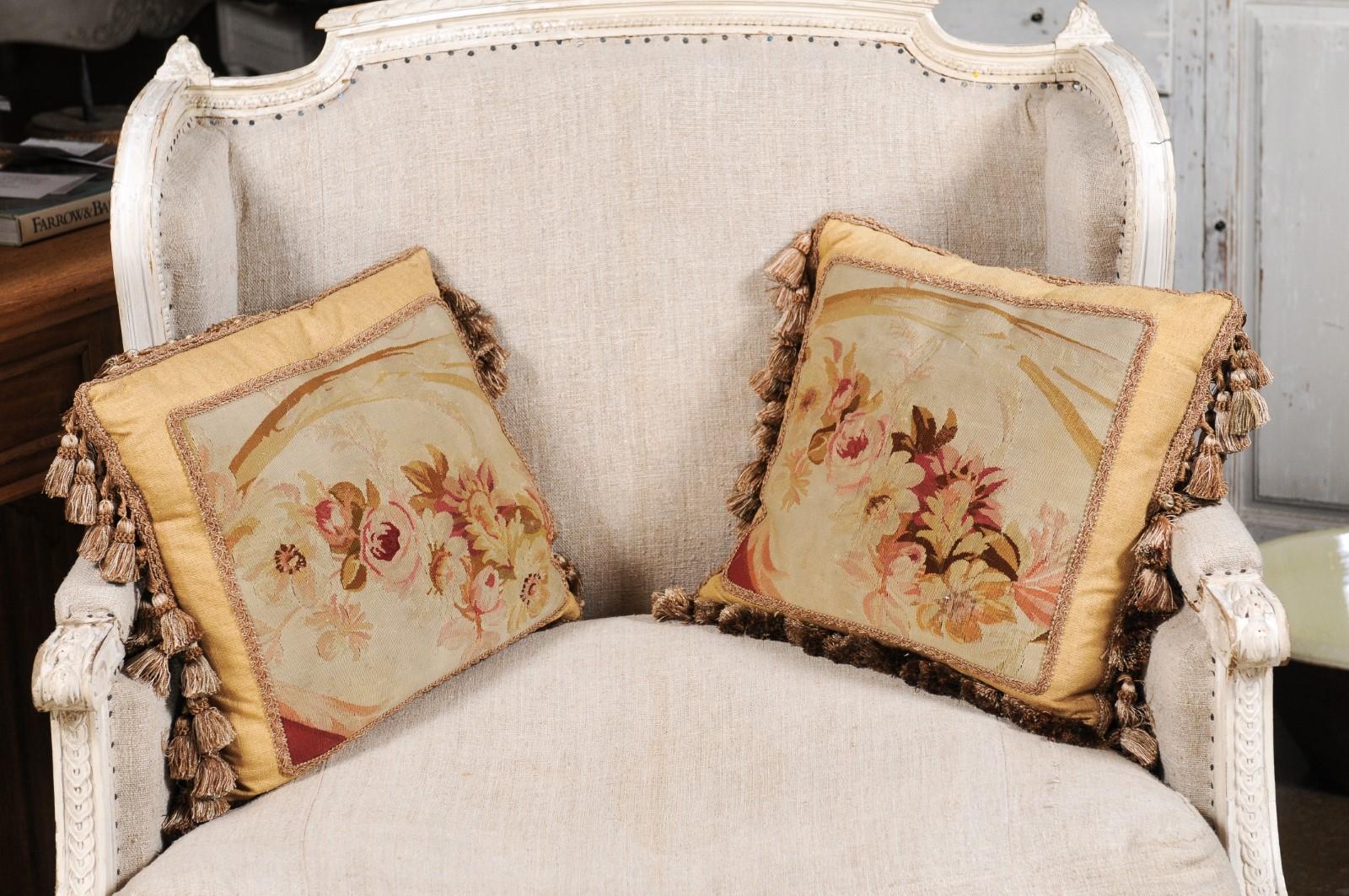 Coppia di cuscini francesi del XIX secolo di forma quadrata in arazzo Aubusson, con decorazioni floreali e nappe. Creati nel XIX secolo nella manifattura di arazzi di Aubusson, nella Francia centrale, questa coppia di cuscini è caratterizzata da