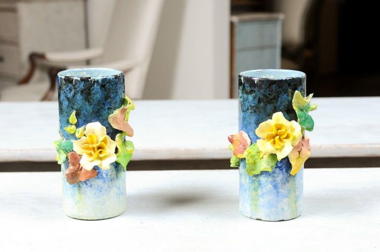 A pair of small French barbotine vases from the 19th century, with colorful flowers and foliage. Born in France during the 19th century, each of this pair of vases features a high-relief floral décor, standing out on a graduating blue ground. The