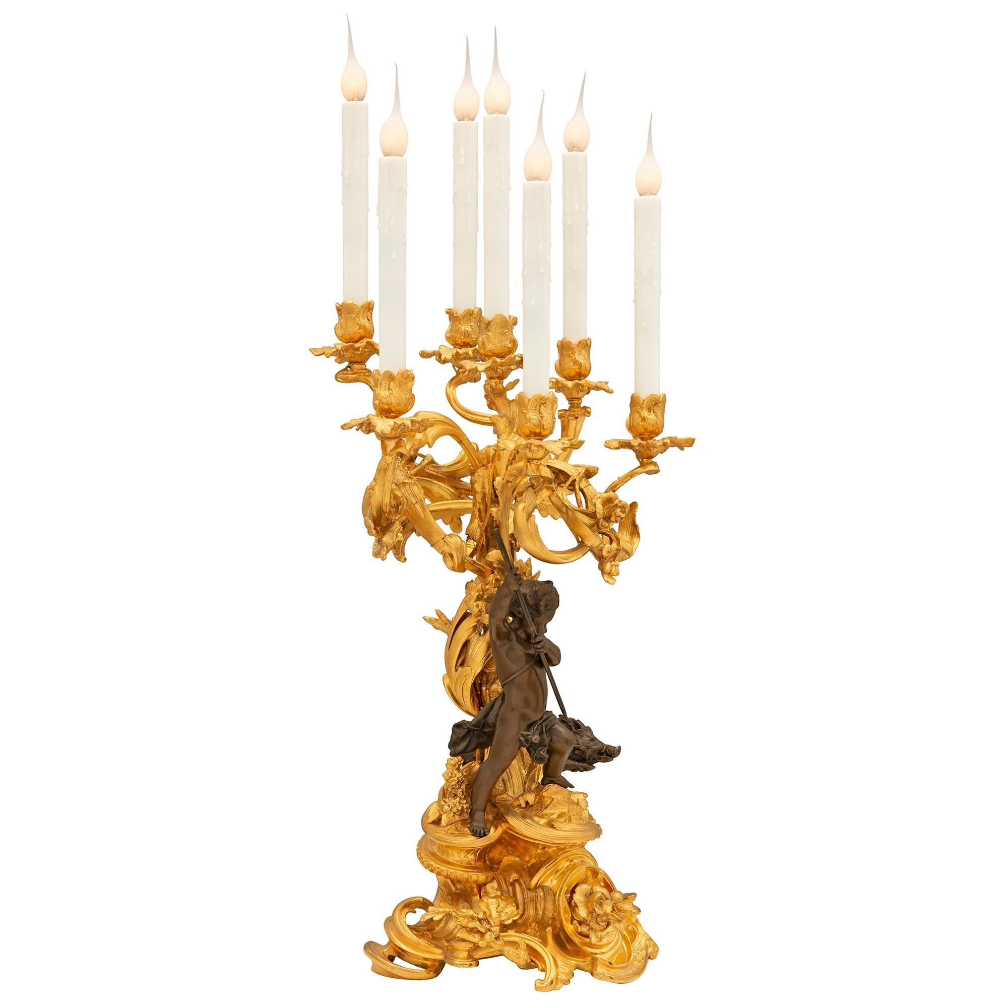 A stunning and monumentally scaled true pair of French 19th century Louis XV st. Belle Époque period ormolu and patinated bronze candelabra lamps. Each extremely high quality seven arm candelabra is raised by a striking and exceptionally well