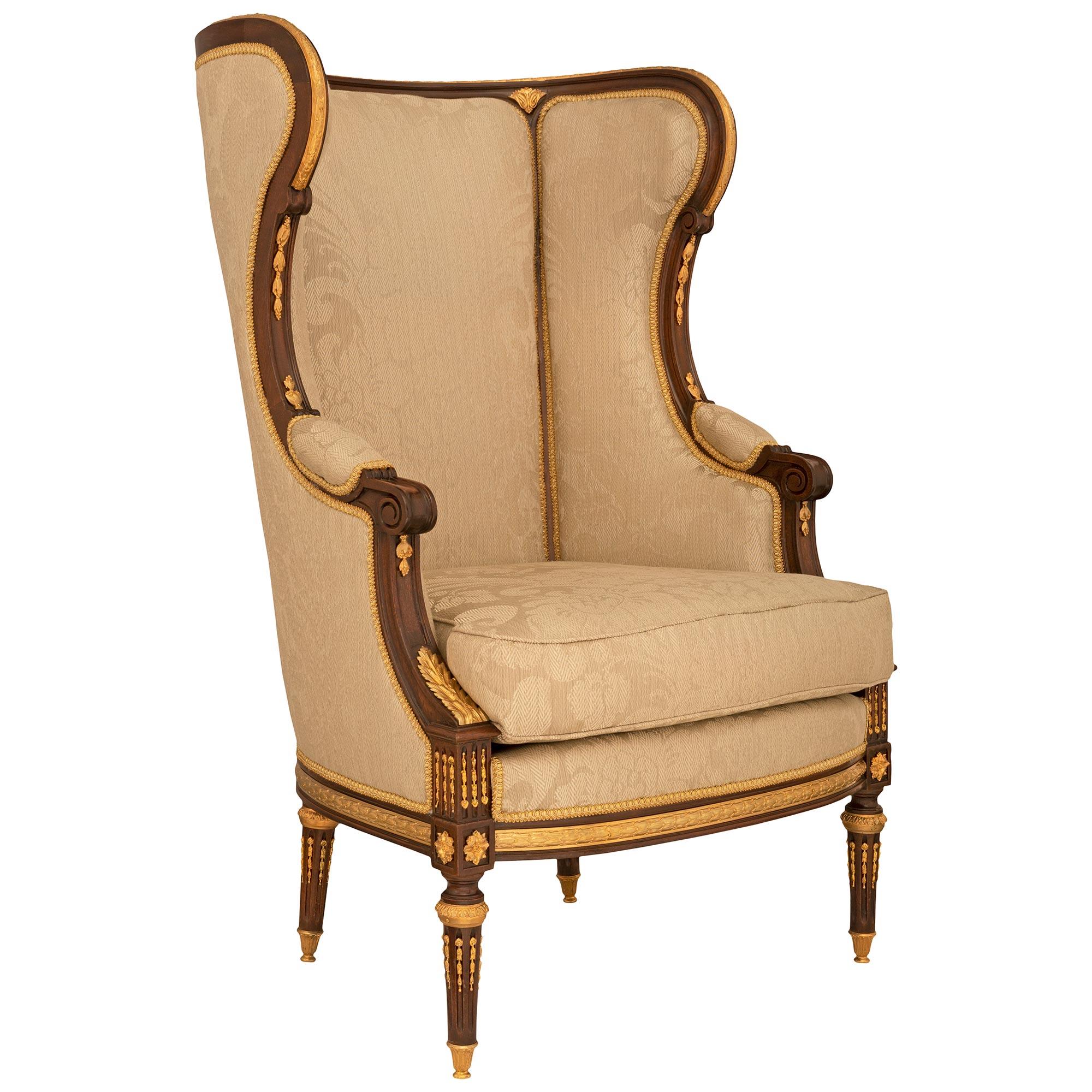 A stunning and high quality pair of French 19th century Louis XVI st. mahogany and ormolu Bergères à Oreilles. Each armchair is raised by elegant circular tapered fluted legs with fine fitted ormolu chandelles, topie shaped feet and beautiful