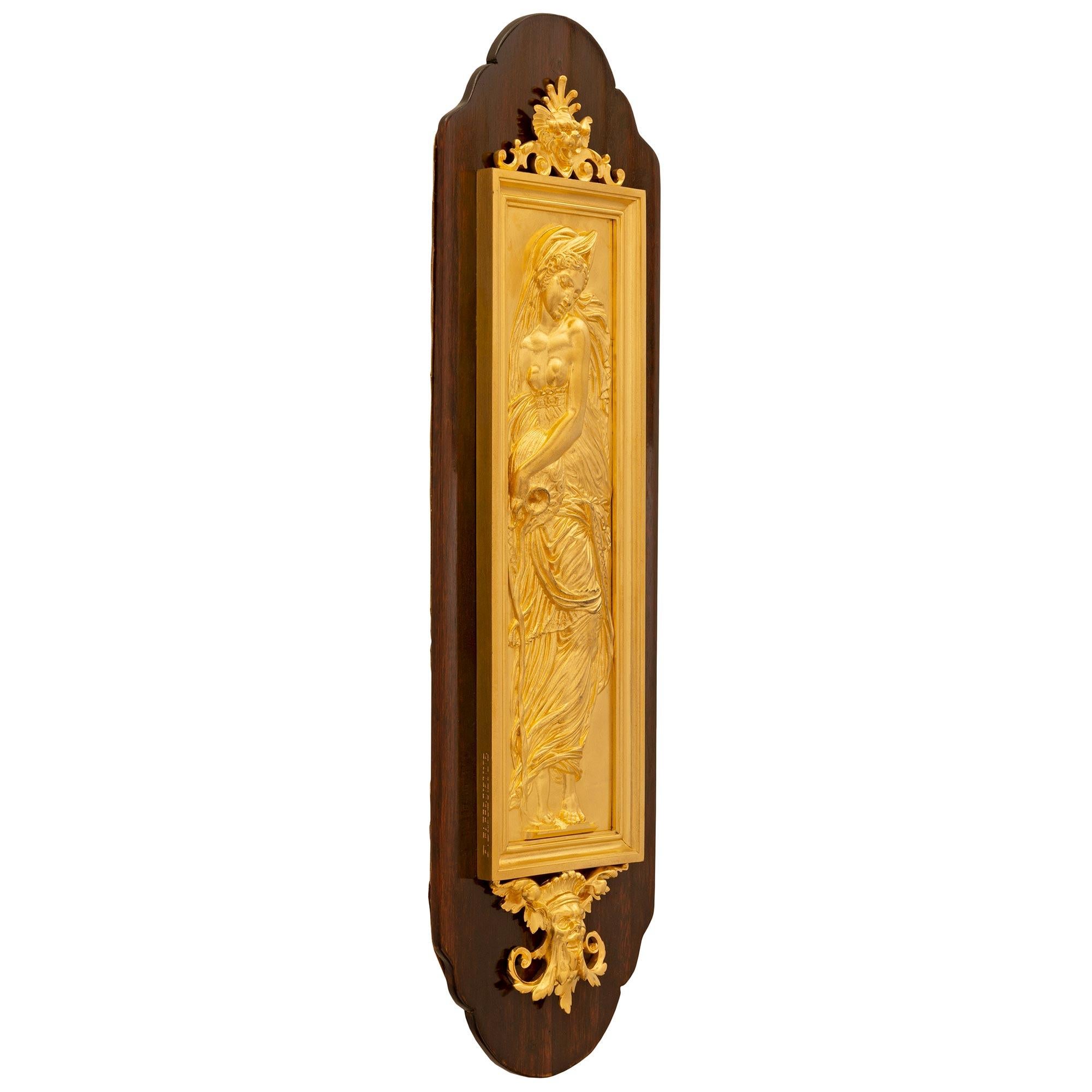 A remarkable pair of French 19th century Louis XVI st. Belle Époque period ormolu and Mahogany decorative wall plaques signed F. Barbedienne. Each plaque is set on an elegant Mahogany backplate with fine scalloped bases and tops. The central ormolu