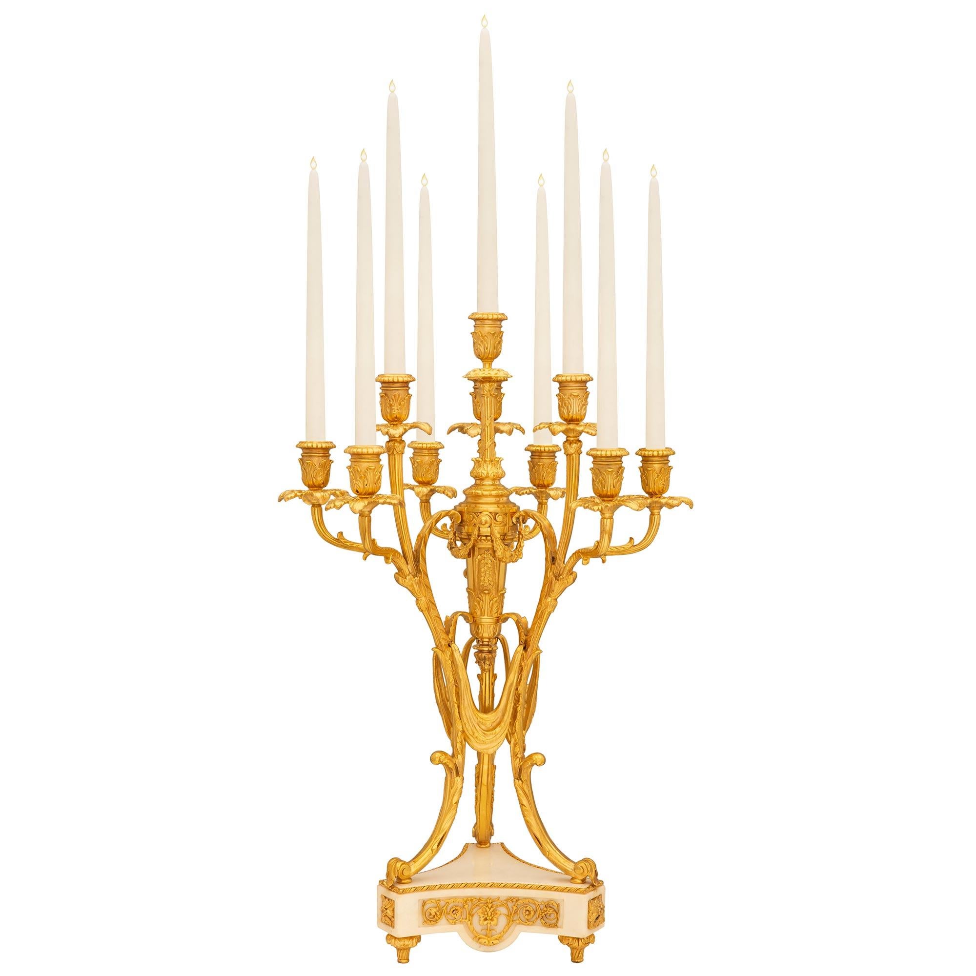 An impressive and high quality pair of French 19th century Louis XVI st. Belle Époque period ormolu and white Carrara marble candelabras. Each ten arm candelabra is raised by a striking triangular white Carrara marble base with fine topie shaped