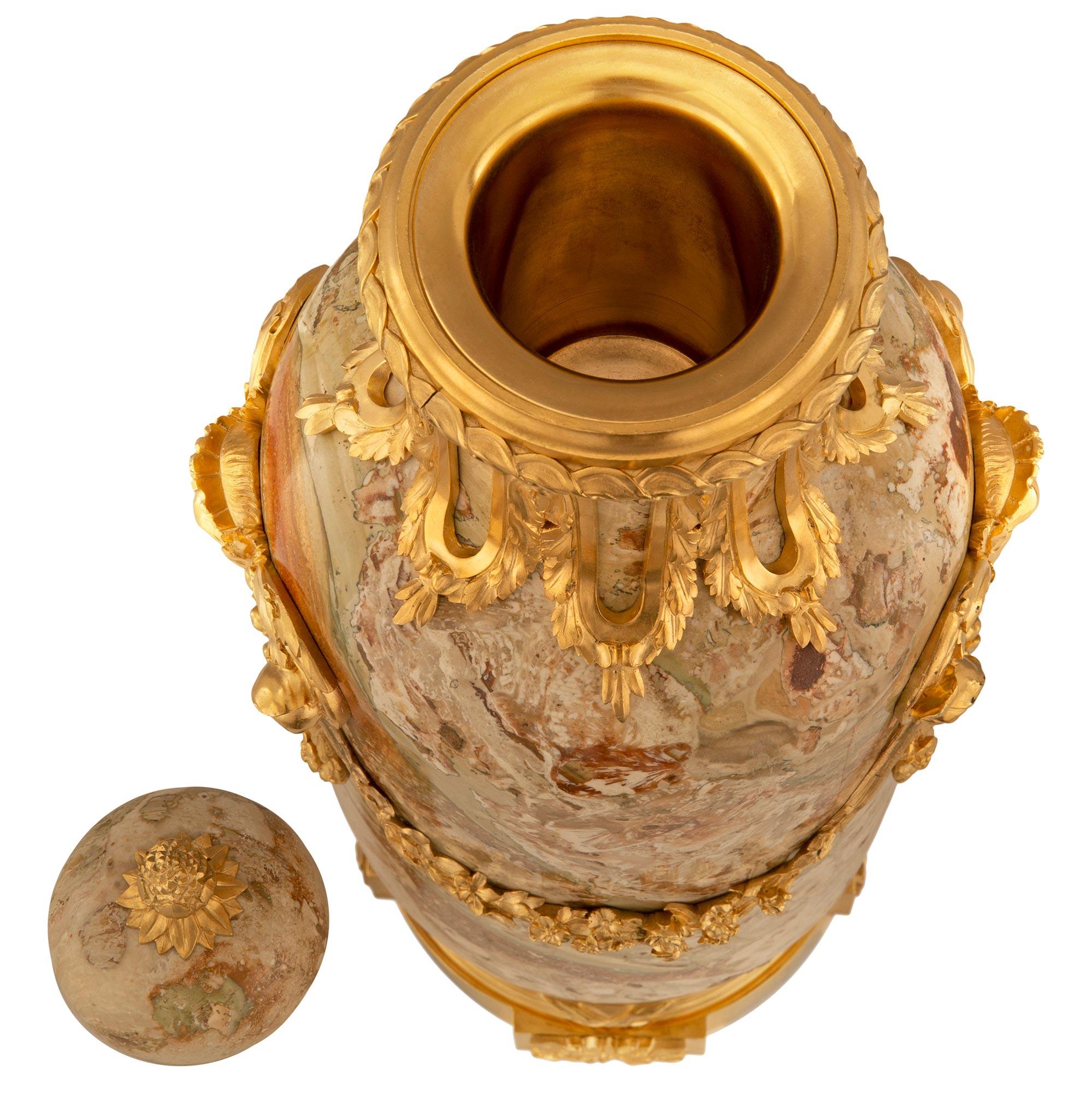 A stunning and very high quality pair of French 19th century Louis XVI st. Belle Époque period ormolu and Sarrancolin marble lidded urns. Each urn is raised by an elegant circular ormolu base with block feet adorned with striking rosettes below a