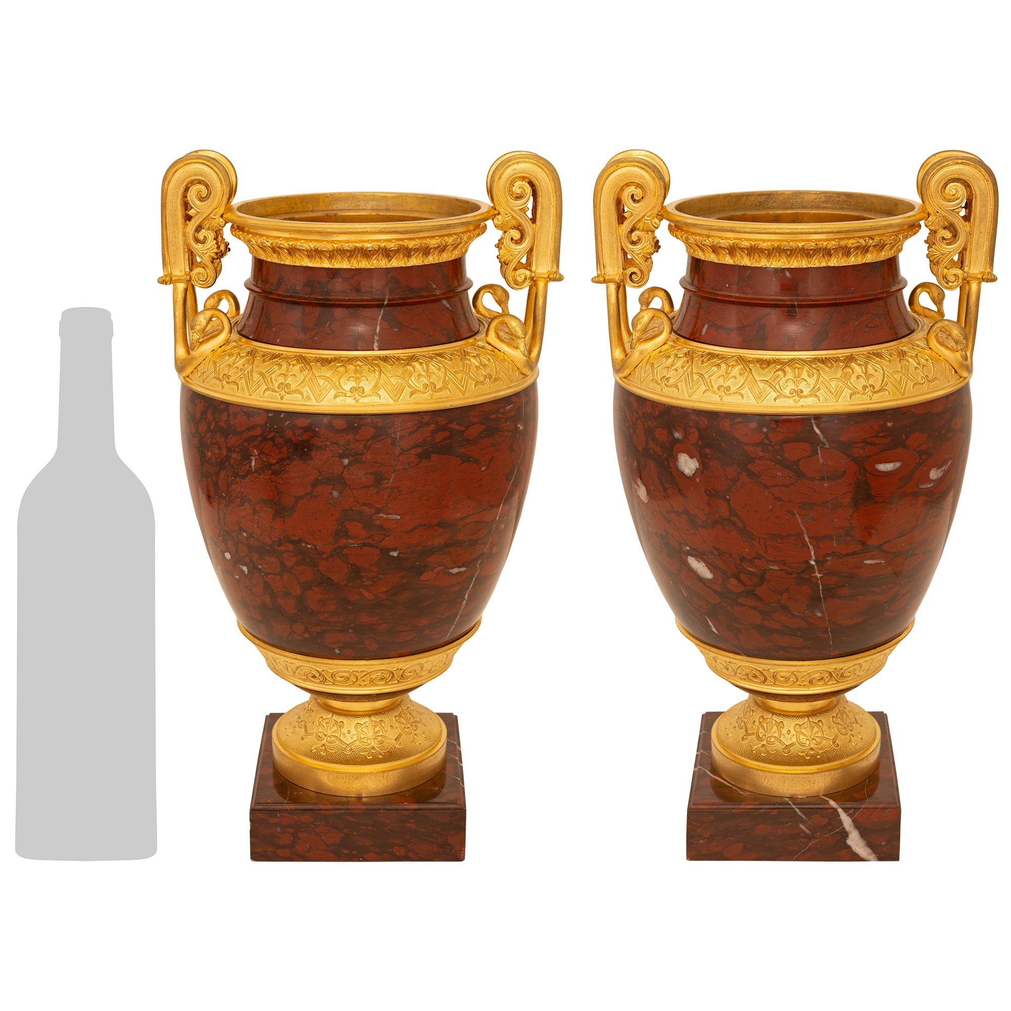 Una bella coppia di urne in stile neo-greco del XIX secolo, di alta qualità. Ormolu e urne in marmo Rouge Griotte. Ogni splendida urna/'Hydria' è sollevata da una base circolare in Ormolu con intricati motivi di scorrimento e sostenuta da una base
