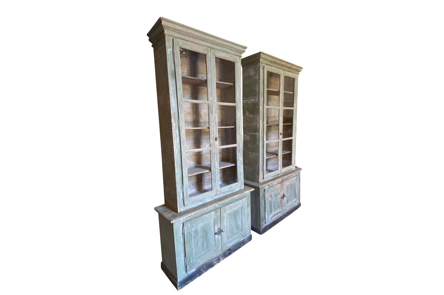 A wonderful pair of Deux Corps Bibliotheques from the Provence region of France.  Soundly constructed from painted pine with each having 4 doors and interior shelving.  Wonderful painted finish.  One bookcase measures 106 3/4