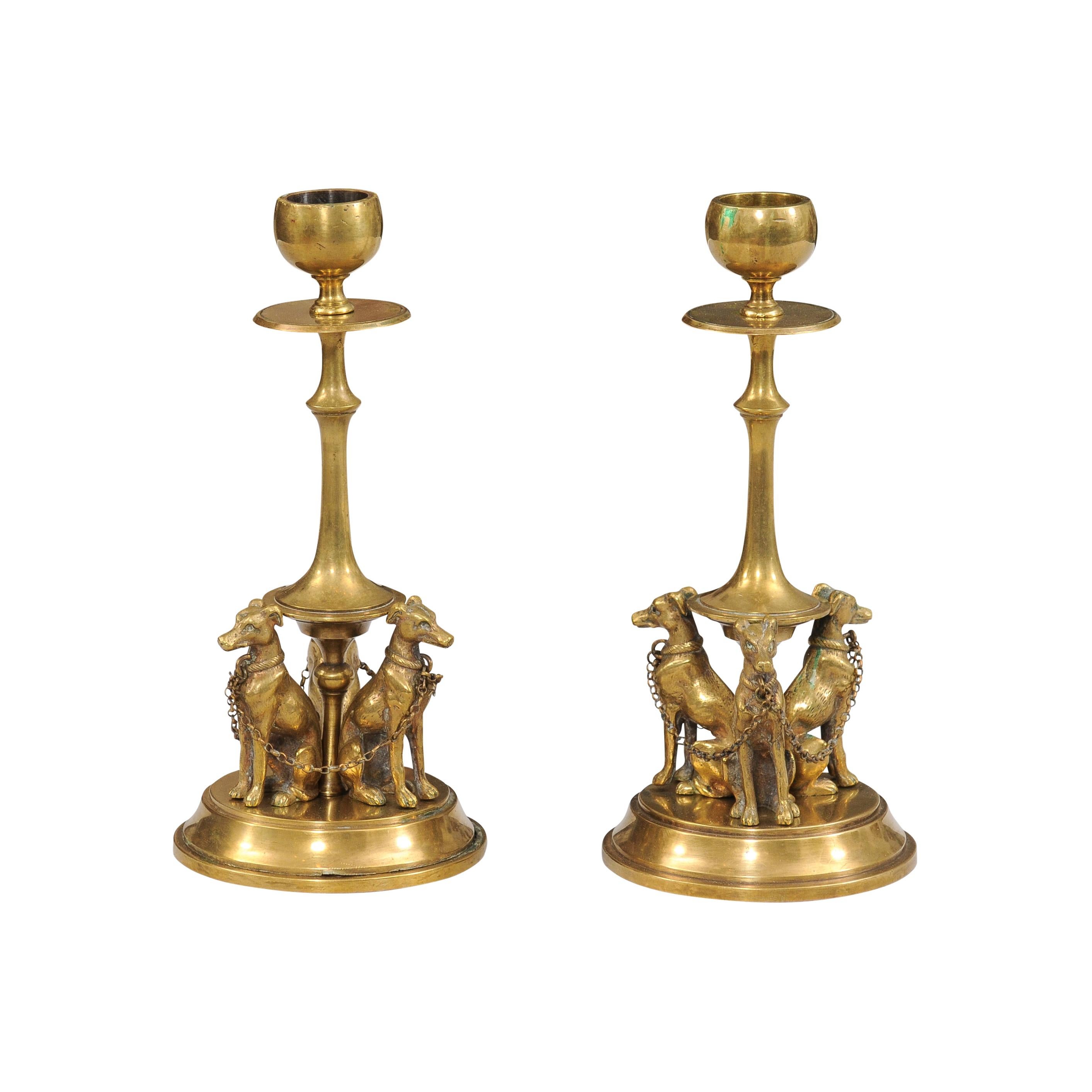 Paire de chandeliers français en bronze du XIXe siècle représentant chacun trois lévriers dans la partie inférieure, reliés l'un à l'autre par des maillons de chaîne ajustés à leur collier. Cette paire de chandeliers en bronze français du XIXe