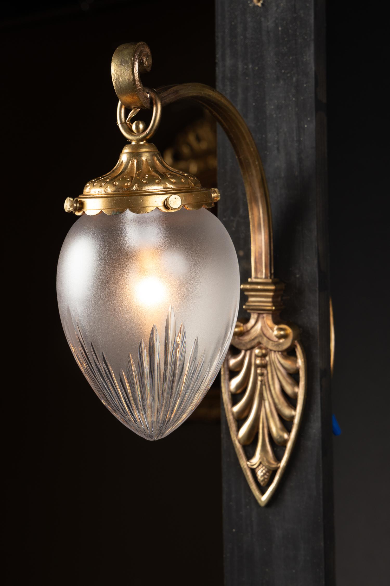 This fantastic pair of bronze sconces features etched satin glass globes at the end of each delicate and detailed scrolling arm. The arms are embellished with a reticulated palmetto leaf back plate which mirrors the movement found in the glass