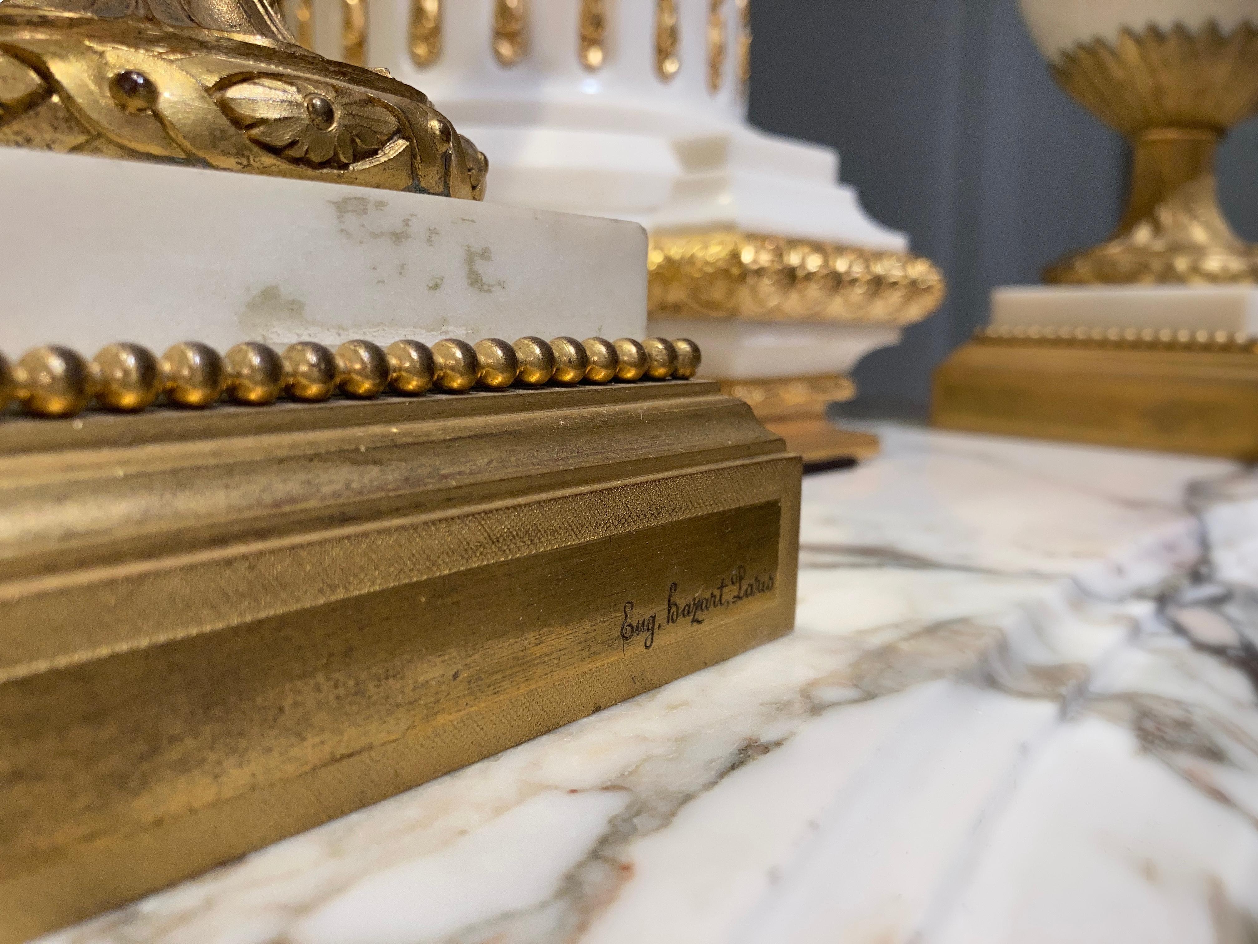 Ein schönes Paar Urnen im Louis XVI-Stil, signiert von Eugene Bazart aus Paris.

Aus Carrara-Marmor und fein gegossener, gehobelter und vergoldeter Bronze; der taillierte, girlandenförmig drapierte Korpus mit Henkeln und Eichelknäufen steht auf
