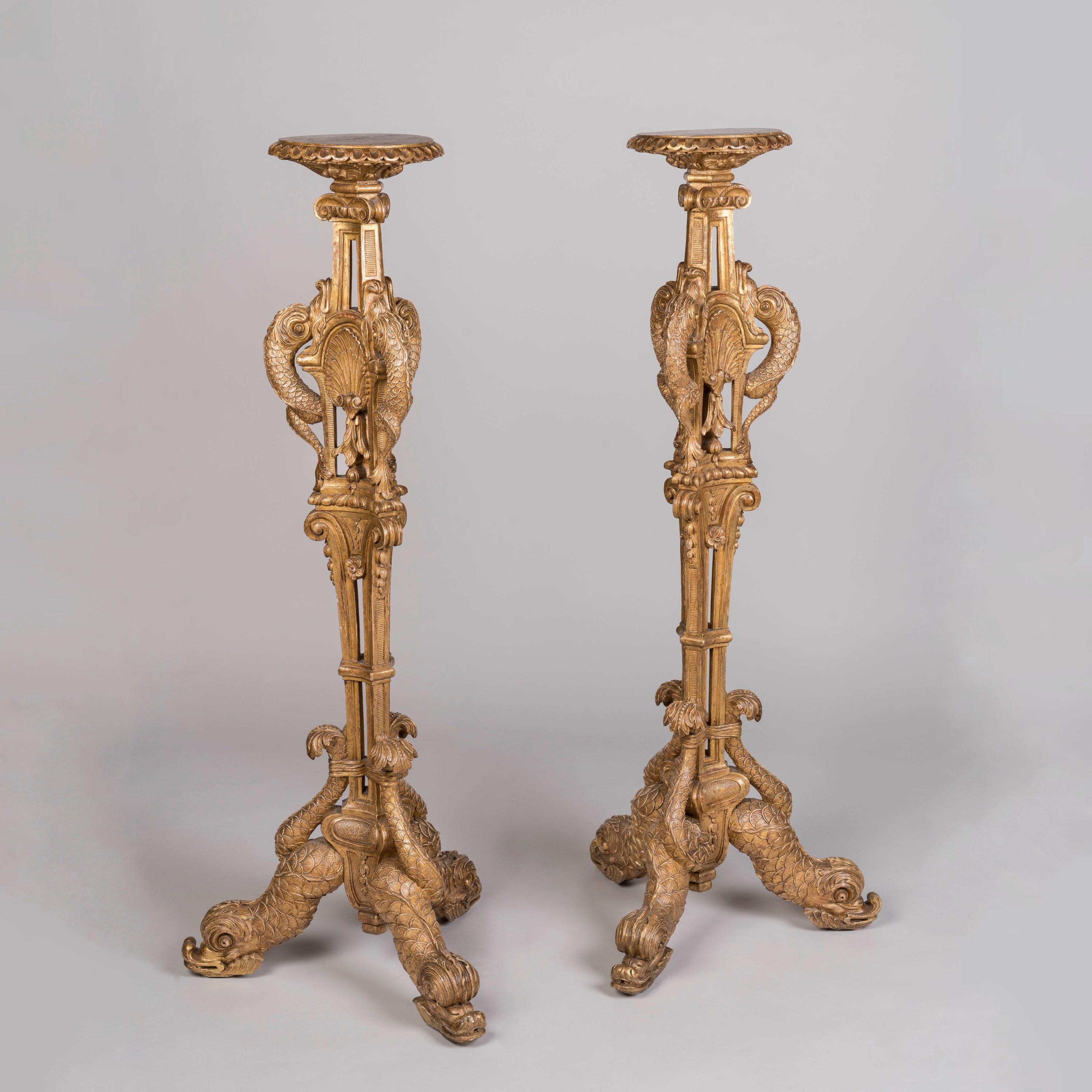 A Pair of Carved Giltwood 'Torchères Aux Dauphins'

A rare and magnificent pair of torchères carved from solid wood, entirely gilded, rising from a tripartite base formed of addorsed and intertwined dolphins gathered around the central clustered