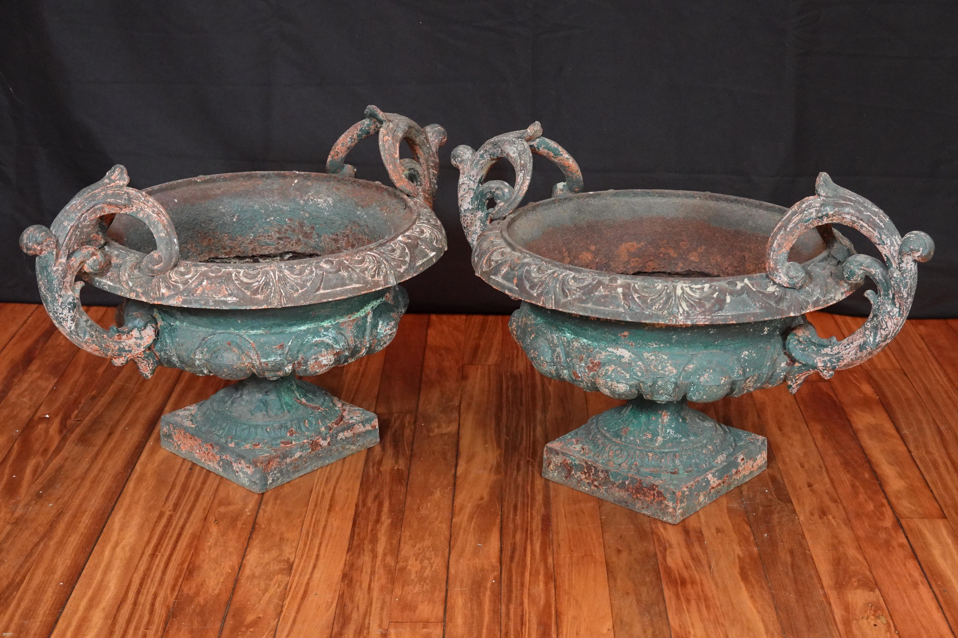 Pair of French 19th century cast iron garden urns with handles. The urns having chipping green paint that add to their beauty.