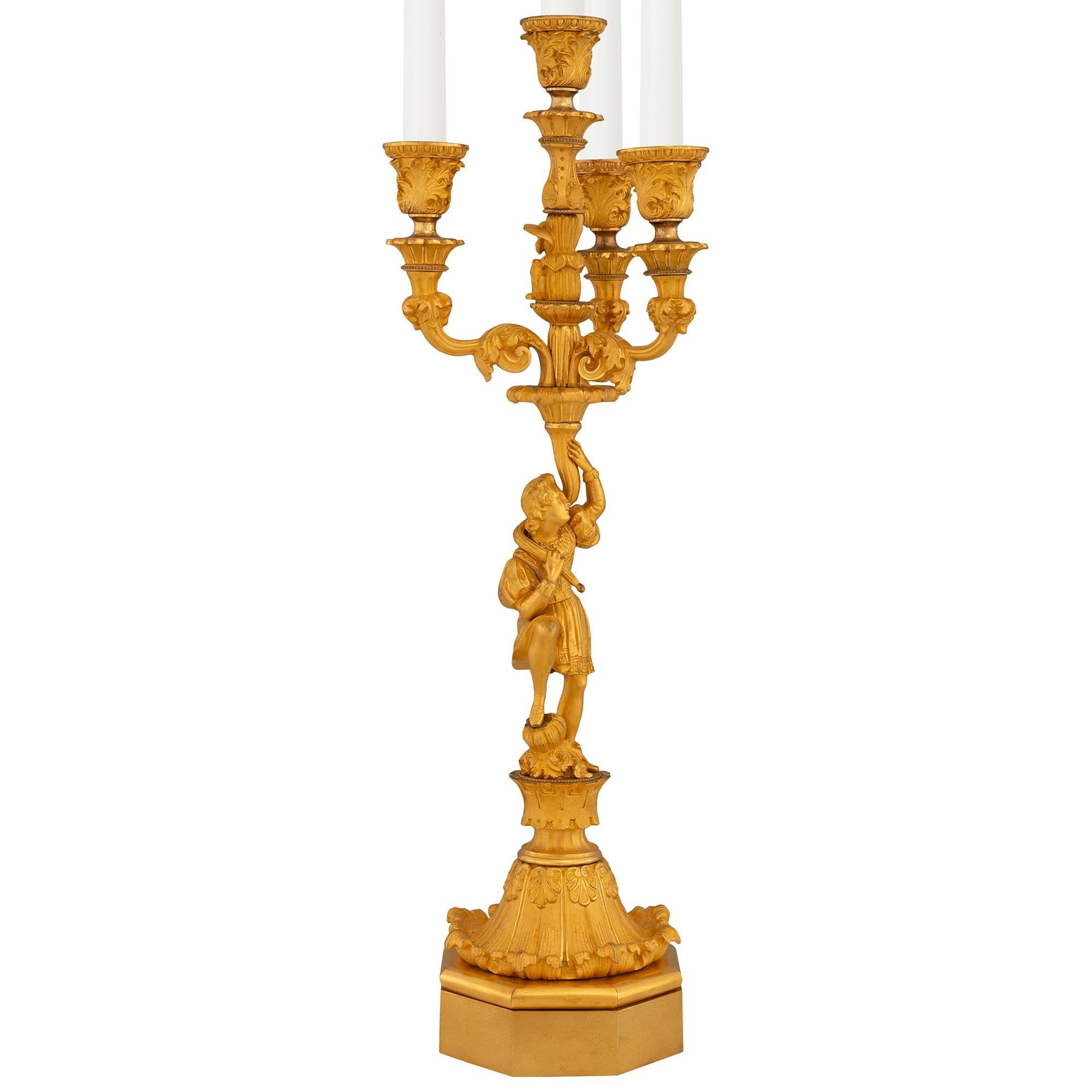 A stunning and true pair of French 19th century Charles X ormolu four arm candelabras. Each candelabra is raised by an octagonal ormolu base below charming richly chased female maidens dressed in classical attire. Each maiden stands on a satin and