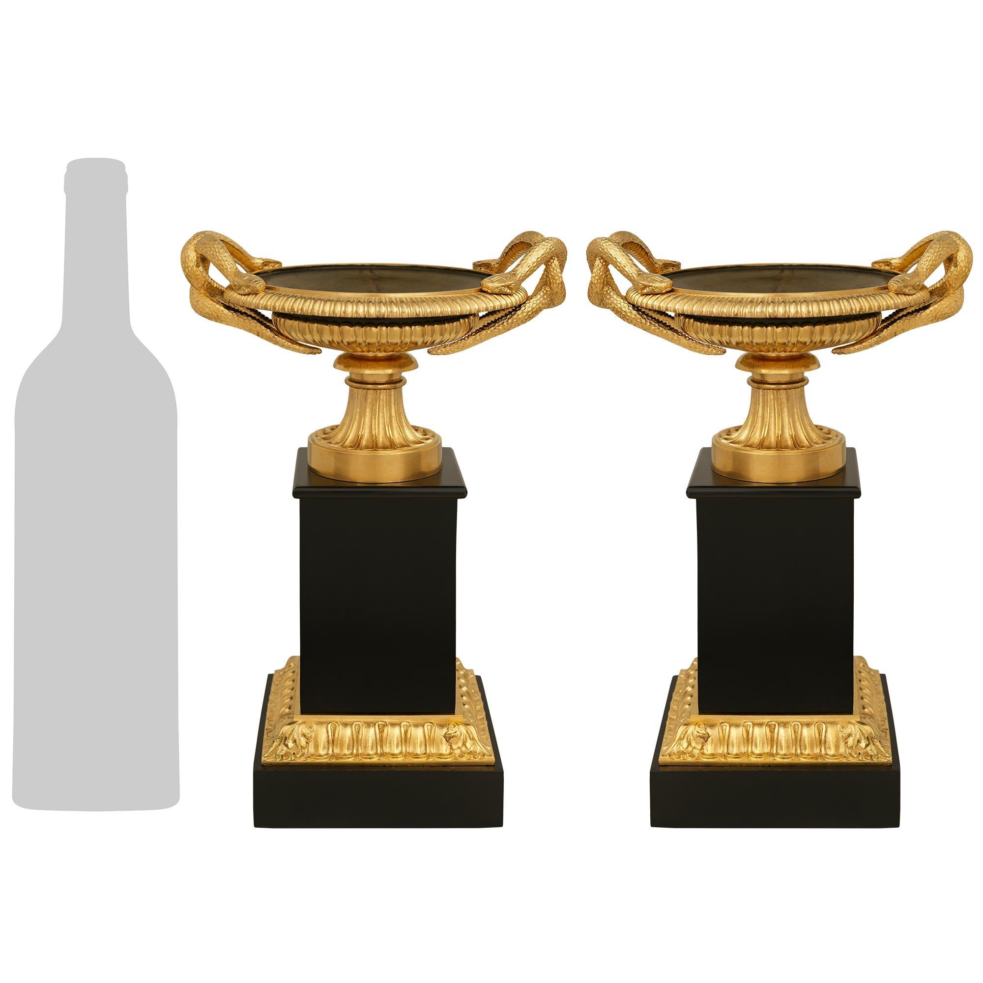 A handsome pair of French 19th century Charles X Period Black Belgian marble, Ormolu and patinated Bronze tazzas. Each handsome tazza is raised by square Black Belgian marble plinth below an Ormolu Rais de Coeur band. Above is the vertical Black