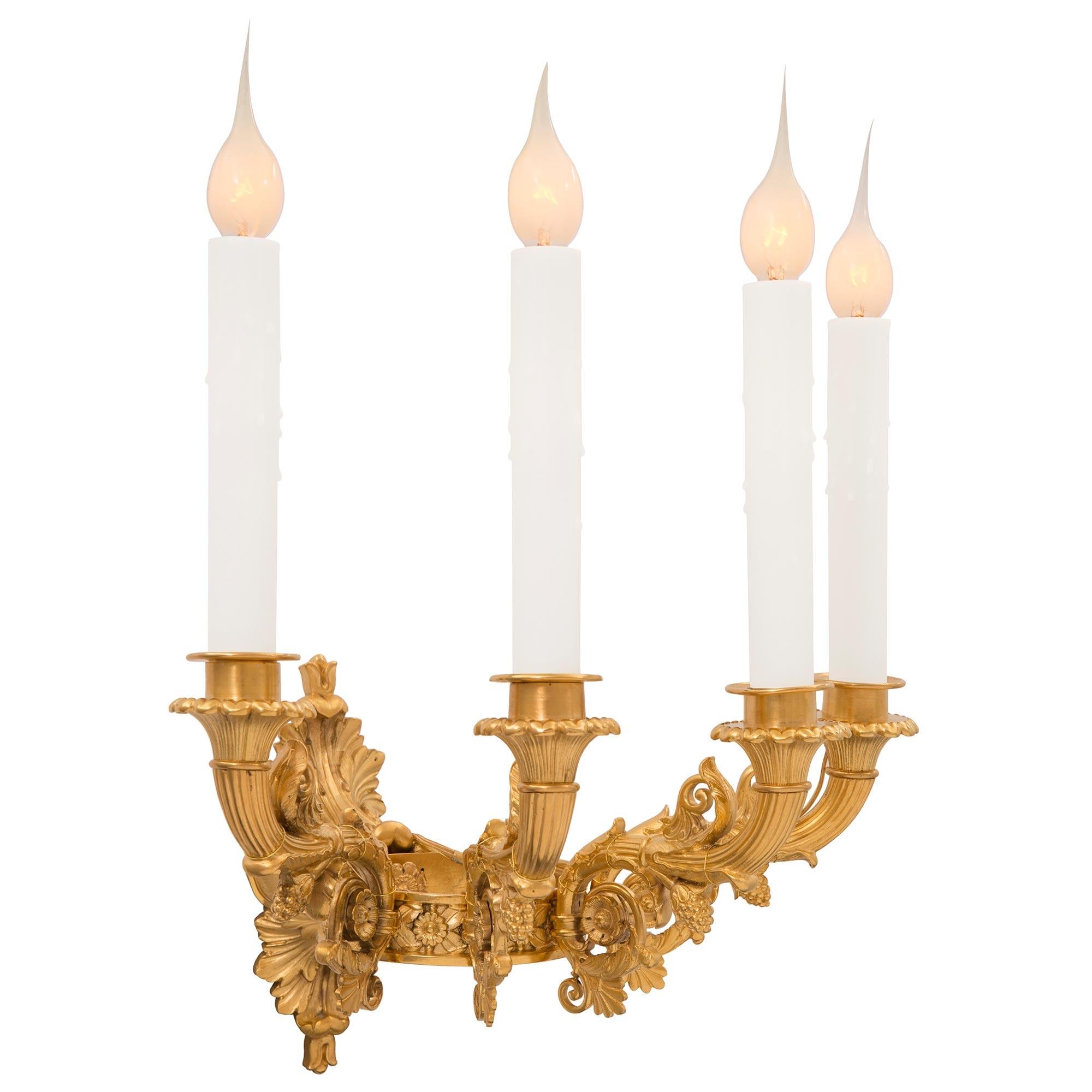A stunning pair of French 19th century Charles X st. ormolu sconces. Each four arm sconce is centered by a beautiful richly chased palmette from where the arms branch out. Each elegantly scrolled arm branches out from a unique crown like ring and