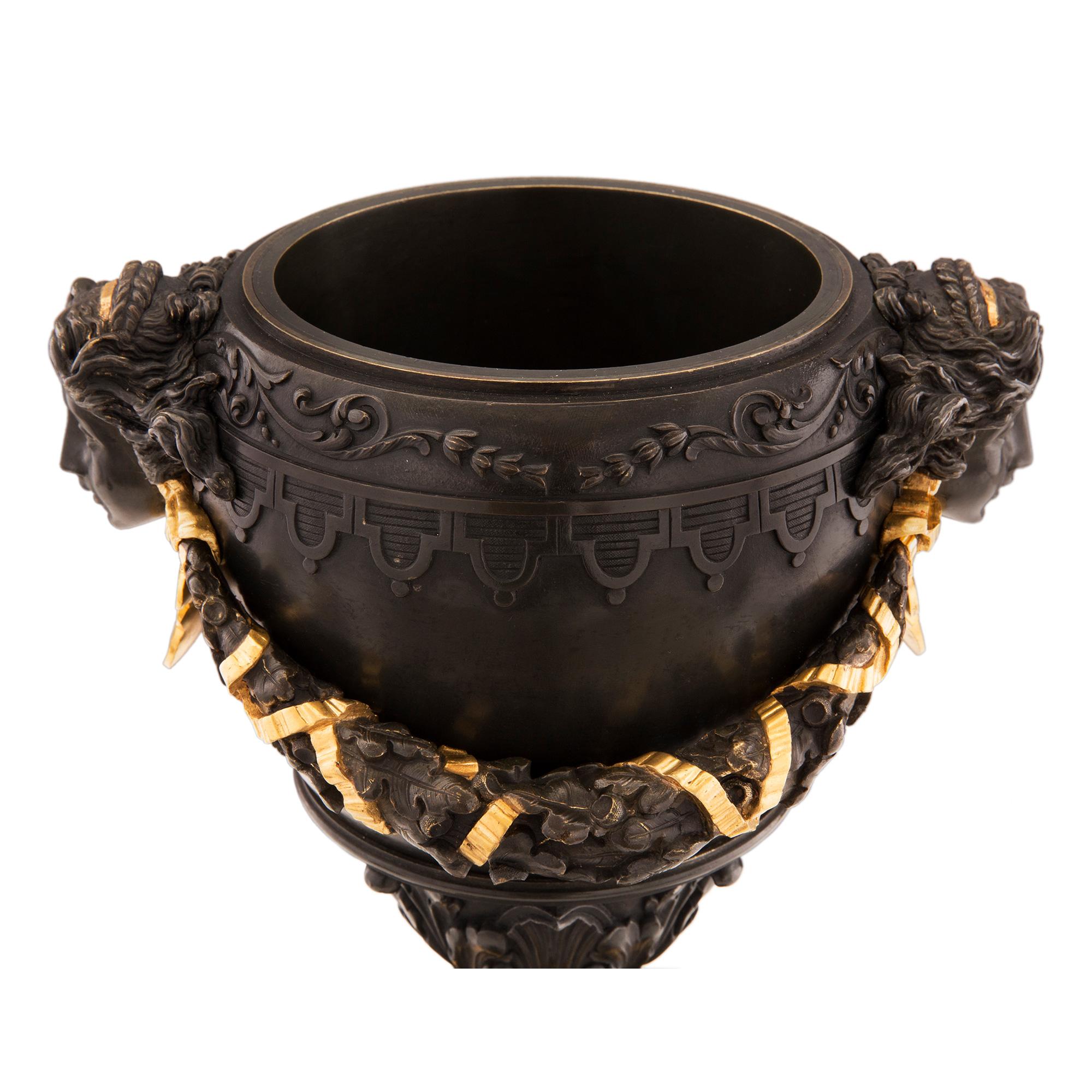 Un'impressionante coppia di urne francesi del XIX secolo in marmo nero belga, bronzo patinato e ormolu. Ogni urna è sollevata da una base quadrata in marmo nero belga con un raffinato filetto inferiore in ormolu e un elegante design a gradini. Al