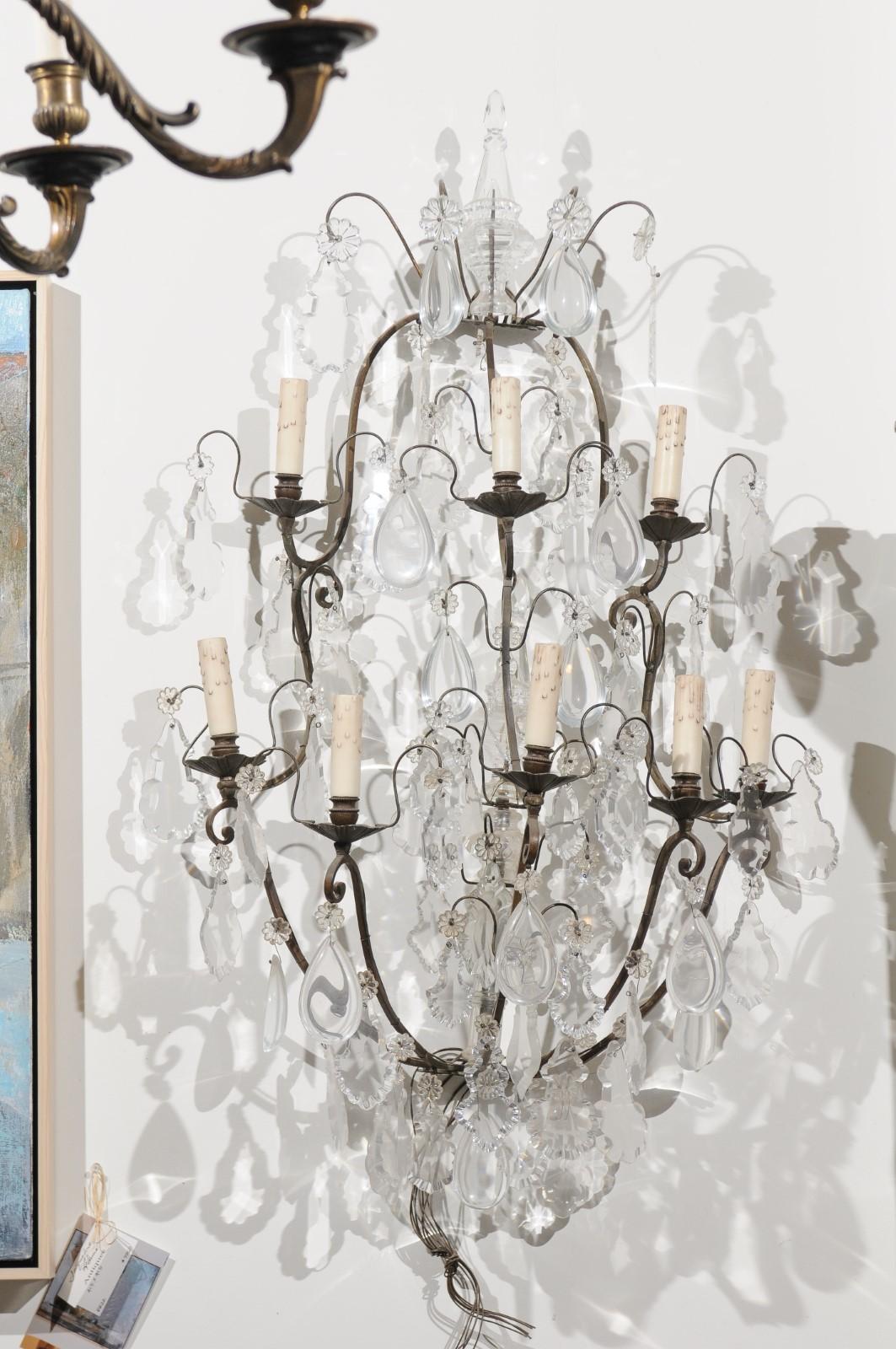 A pair of French crystal eight-light wall sconces from the 19th century, with iron armature. Born in France during the 19th century, each of this pair of sconces is topped with a crystal obelisk, surrounded by delicate scrolls supporting delicate