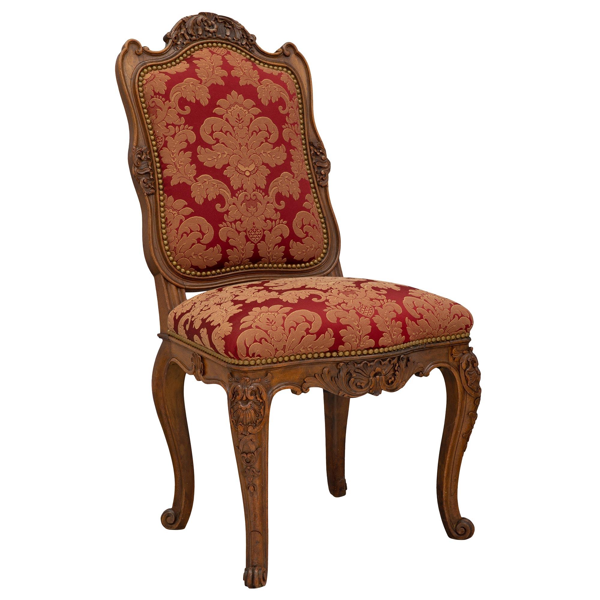 A fine pair of French 19th century Louis XV st. dark oak chairs. Each chair is raised by elegant cabriole legs and handsomely decorated with carvings of shells, acanthus leaves, and scrolls, which continue at the frieze. The back of each chair back