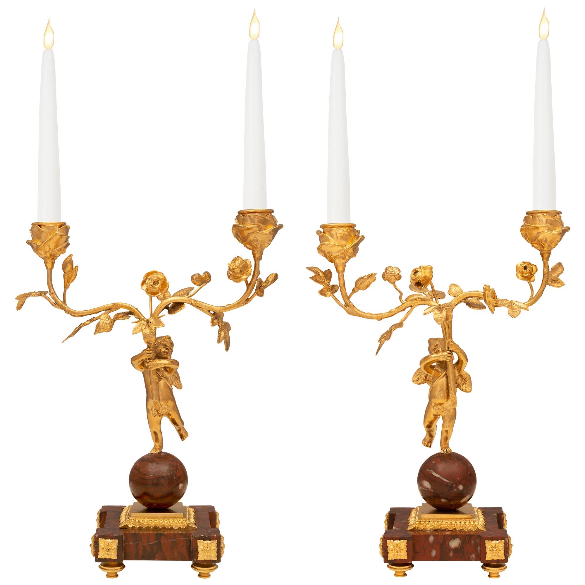 A stunning and most charming pair of French 19th century Louis XVI st. Belle Époque period ormolu and Rouge Griotte marble candelabras. The two arm candelabra are raised by beautiful square Rouge Griotte marble bases with fine topie shaped feet and