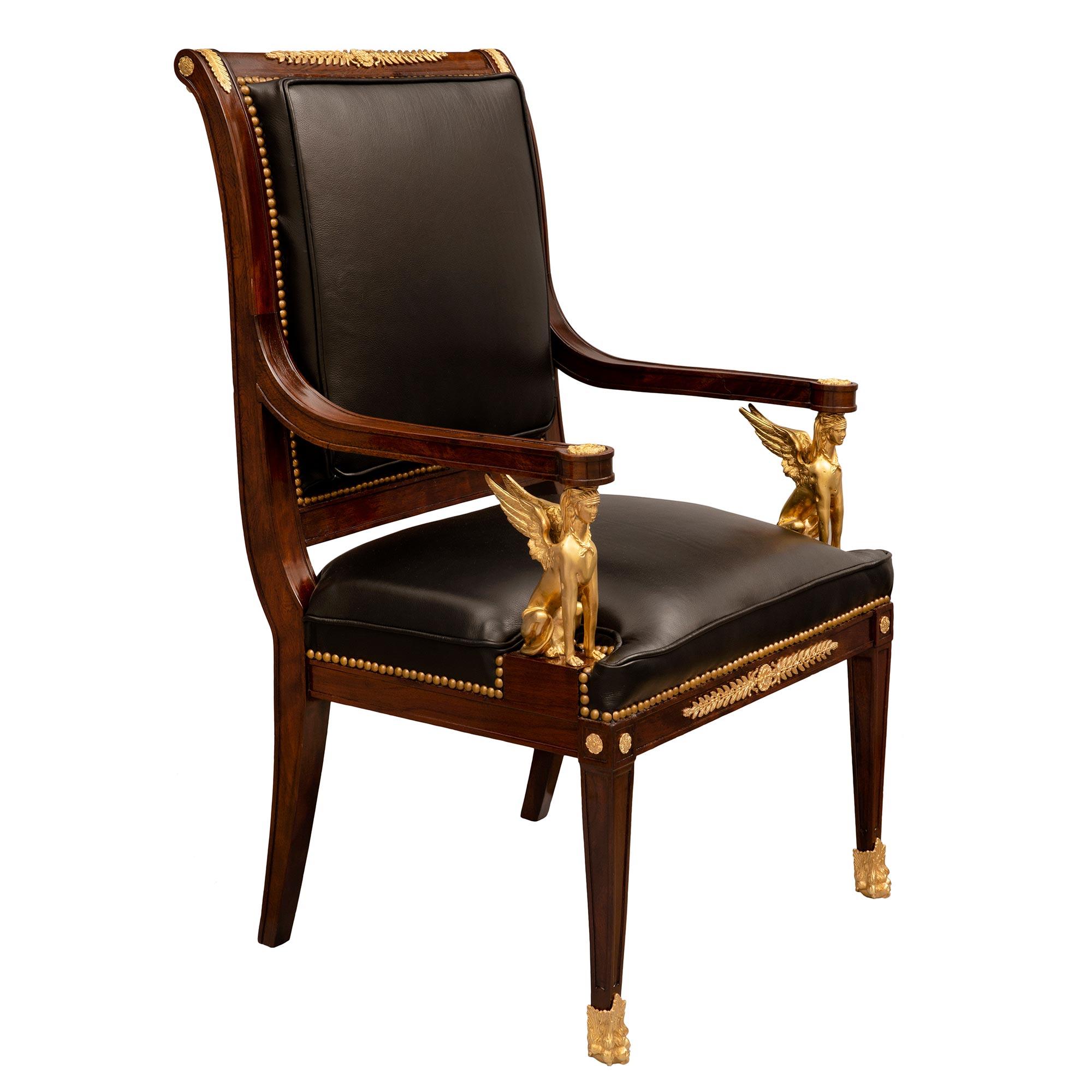 A handsome and most impressive pair of French 19th century Empire st. Belle Époque period mahogany and ormolu armchairs. Each armchair is raised by square tapered legs with richly chased paw feet and finely carved recessed panels at the front, and