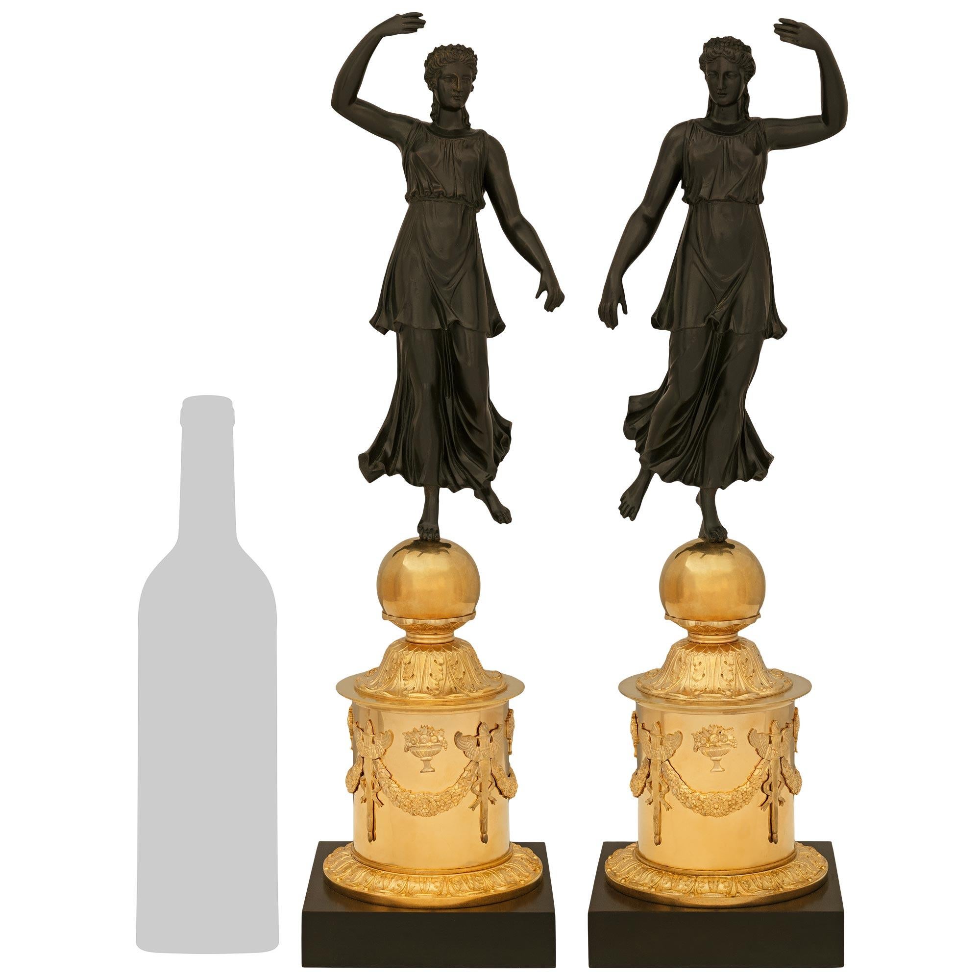 An elegant and high quality pair of French 19th century Empire st. Ormolu and patinated Bronze statues. Each wonderfully decorative statue of a dancing maiden is raised on a square patinated Bronze plinth below a cylindrical pedestal. The pedestals
