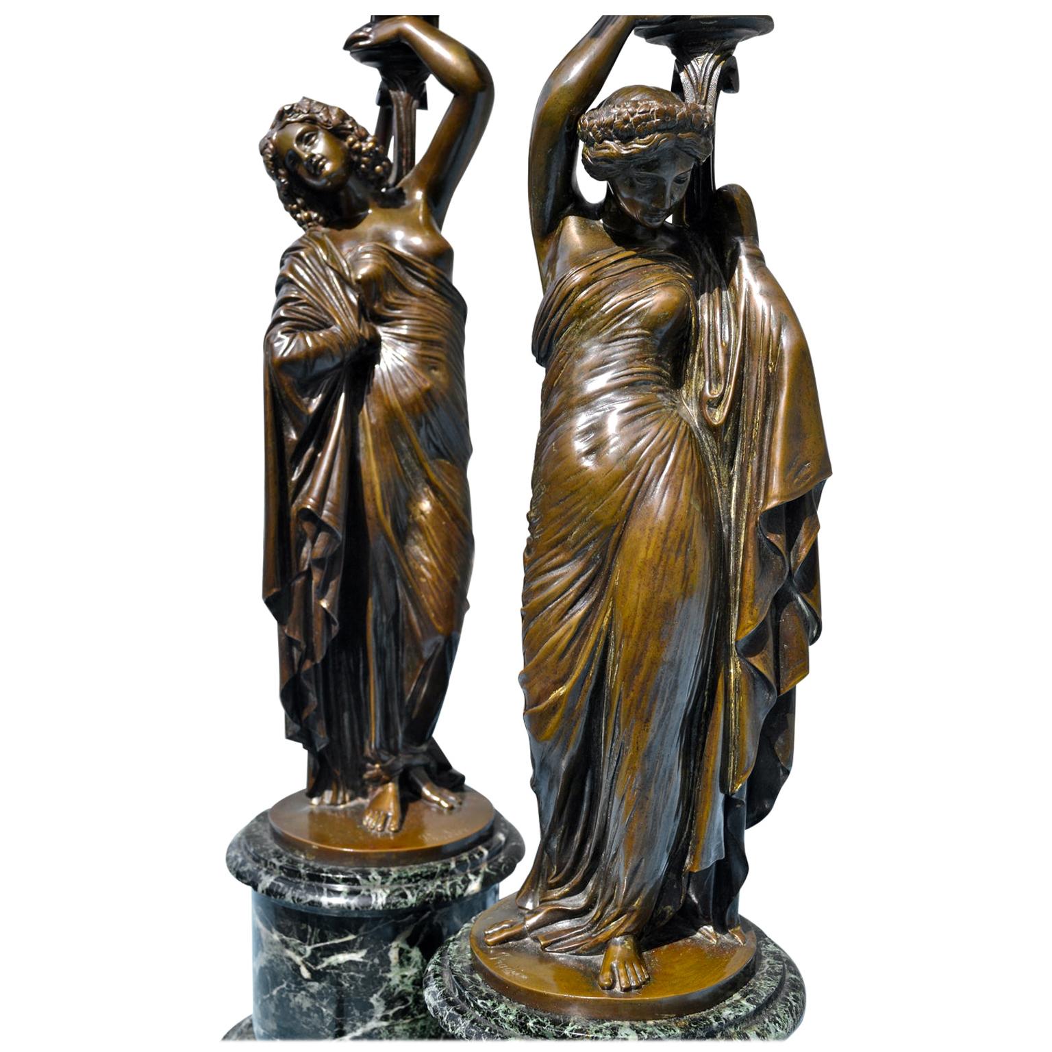 A beautifully cast pair of French 19th century neoclassical patinated figural bronze nine arm candelabra after a model by Jaen Jacques Pradier They are signed J. Pradier and were converted into lamps in the 20th century. Each candelabra is cast as