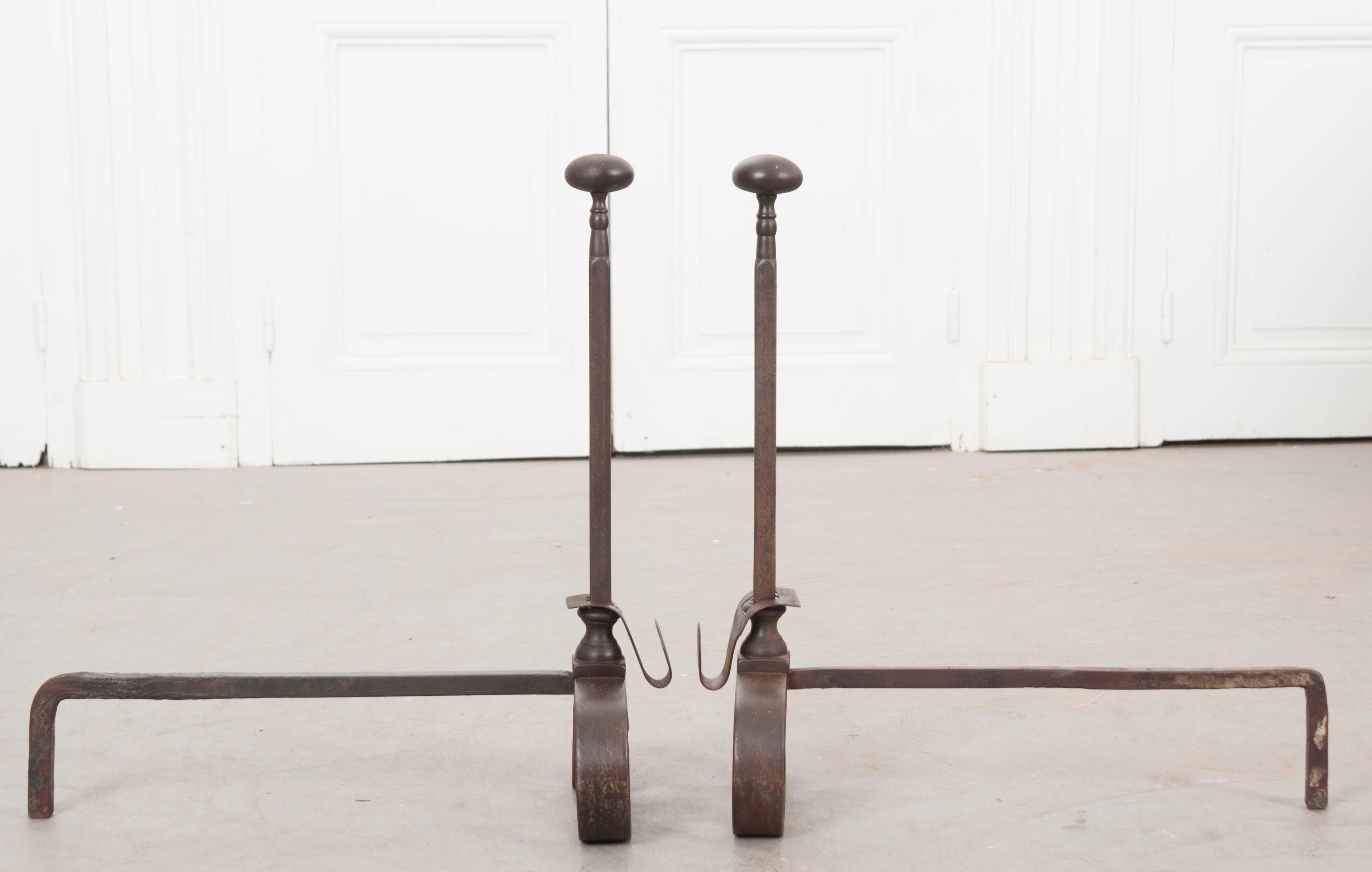 This fine and heavy pair of columnar iron andirons, circa 1850s, were made in France. The iron has taken on a lovely patina thanks to years of fires enjoyed by the previous owners. The design is conservative and Classic, with scrolled iron front
