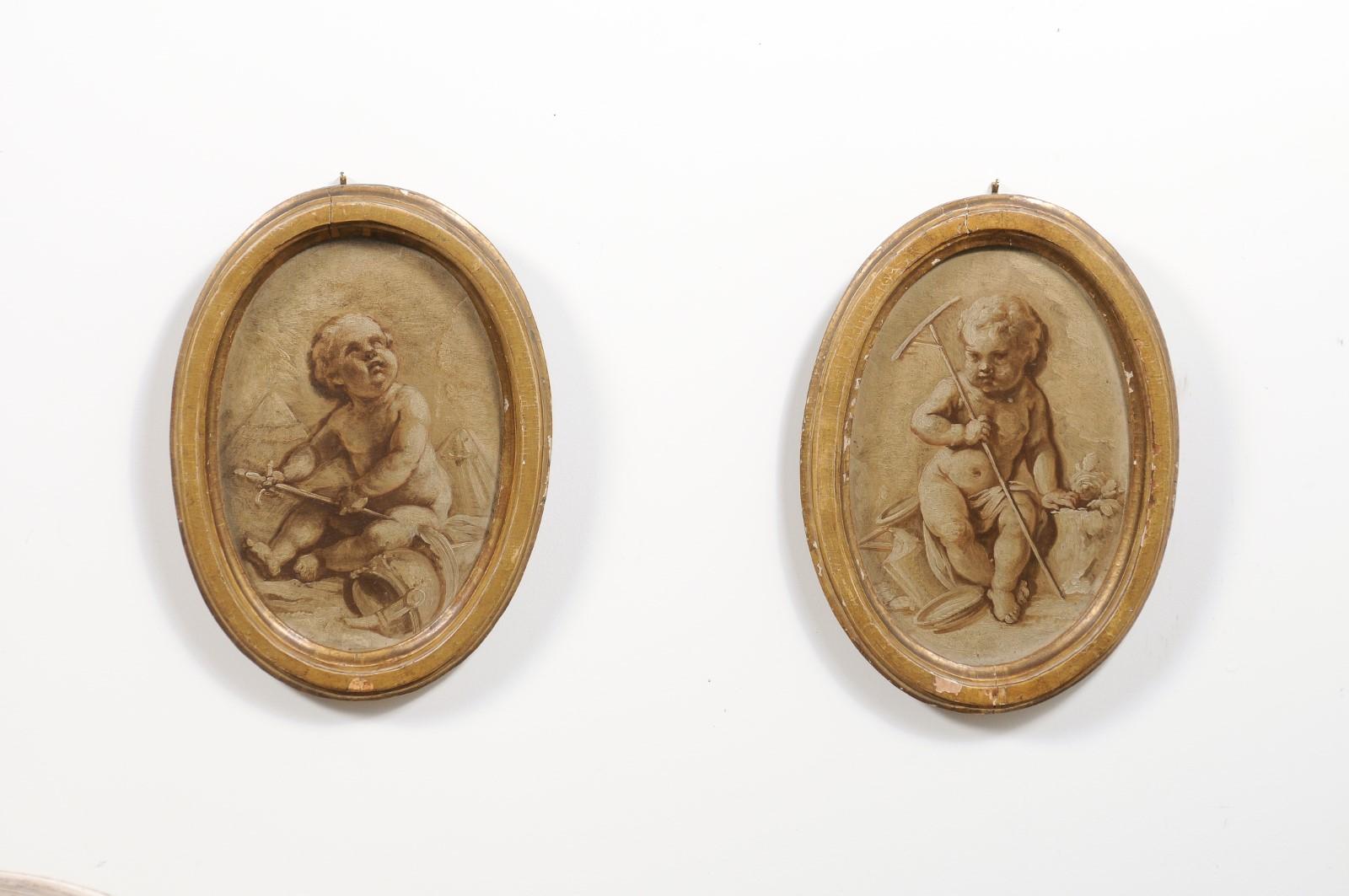 A pair of French framed oval grisaille paintings from the 19th century, depicting two putti. Created in France during the 19th century, each of this pair of grisailles features an oval frame boasting a nicely weathered patina, surrounding a chubby