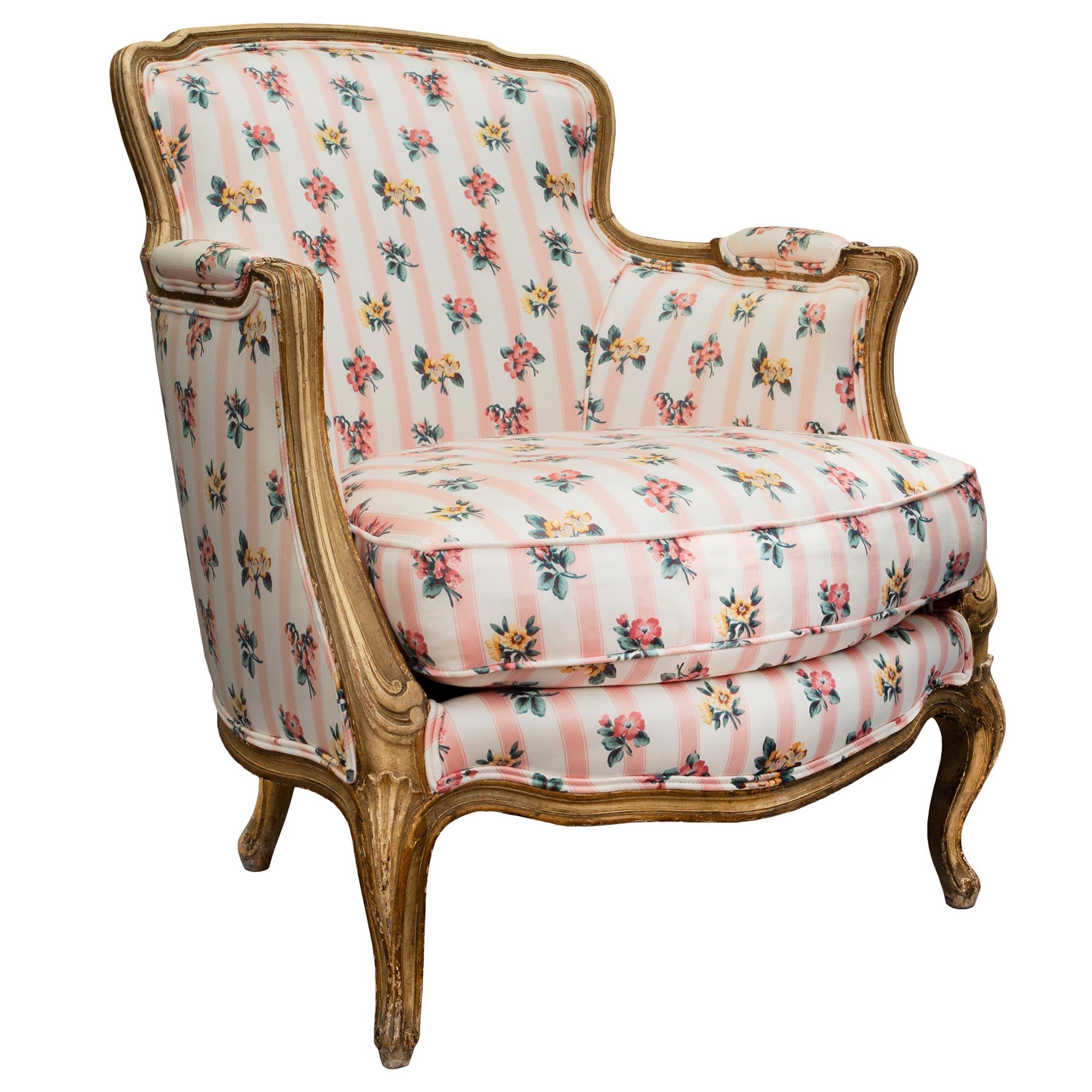 A charming pair of French 19th century French Louis XV st. patinated Bergères. Each armchair is raised by carved cabriole legs with hints of gilt. The curved frieze continues to the upholstered armrest and the curved wide back. All original patina.