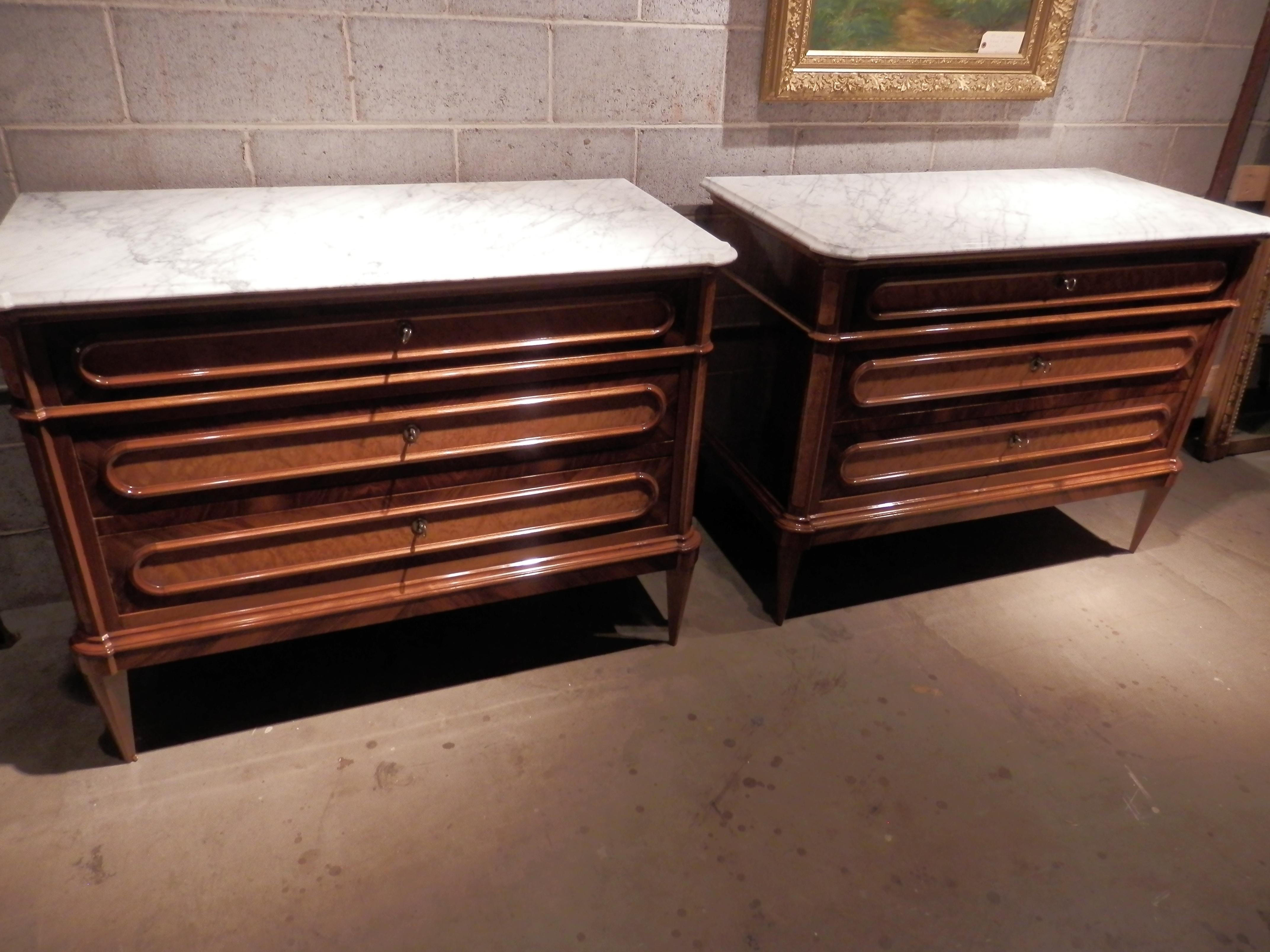 Beautiful pair of 19th century French Louis XVI walnut and fruitwood inlayed and burled commodes with the original carerra marble tops. Beautiful woods and inlay.