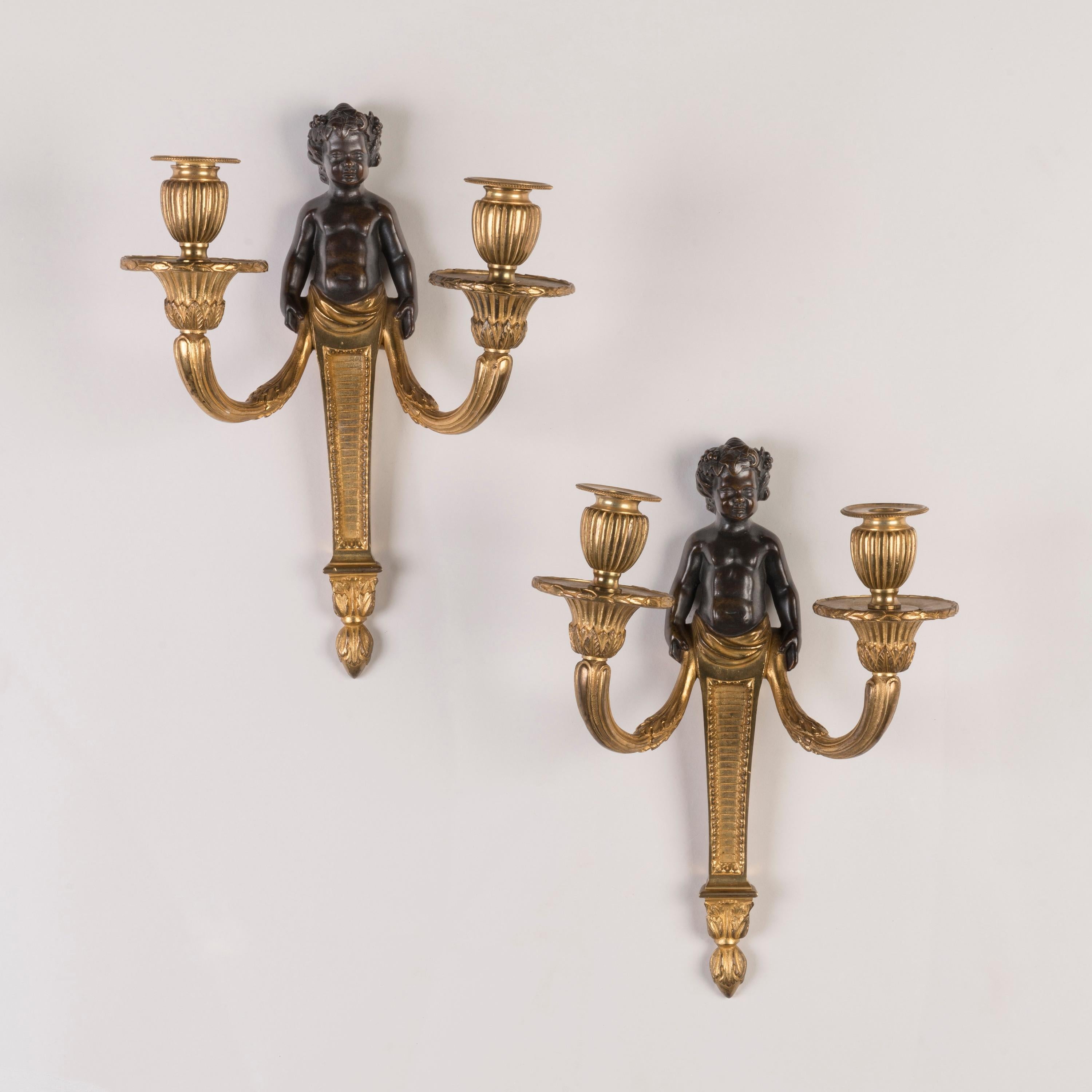 Un par de apliques de pared estilo Luis XVI

Construidos en bronce patinado y dorado al fuego, con detalles grabados a mano, la pareja de apliques está modelada como dos términos bacanales de jóvenes, cada uno de los cuales sostiene dos brazos