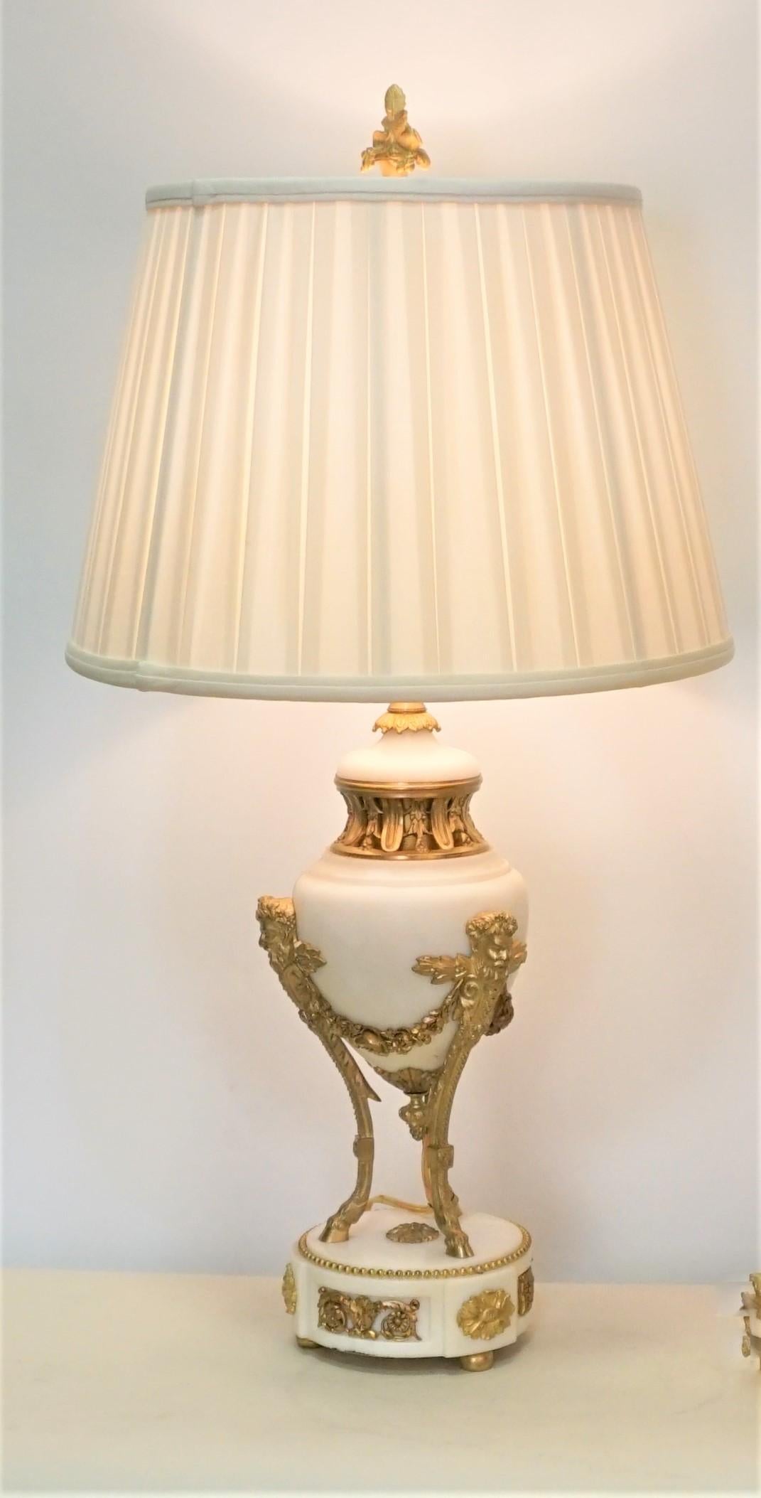 Pair of 19th century gilt bronze and white marble urns that have been electrified.
Fitted with silk box pleat lampshades.