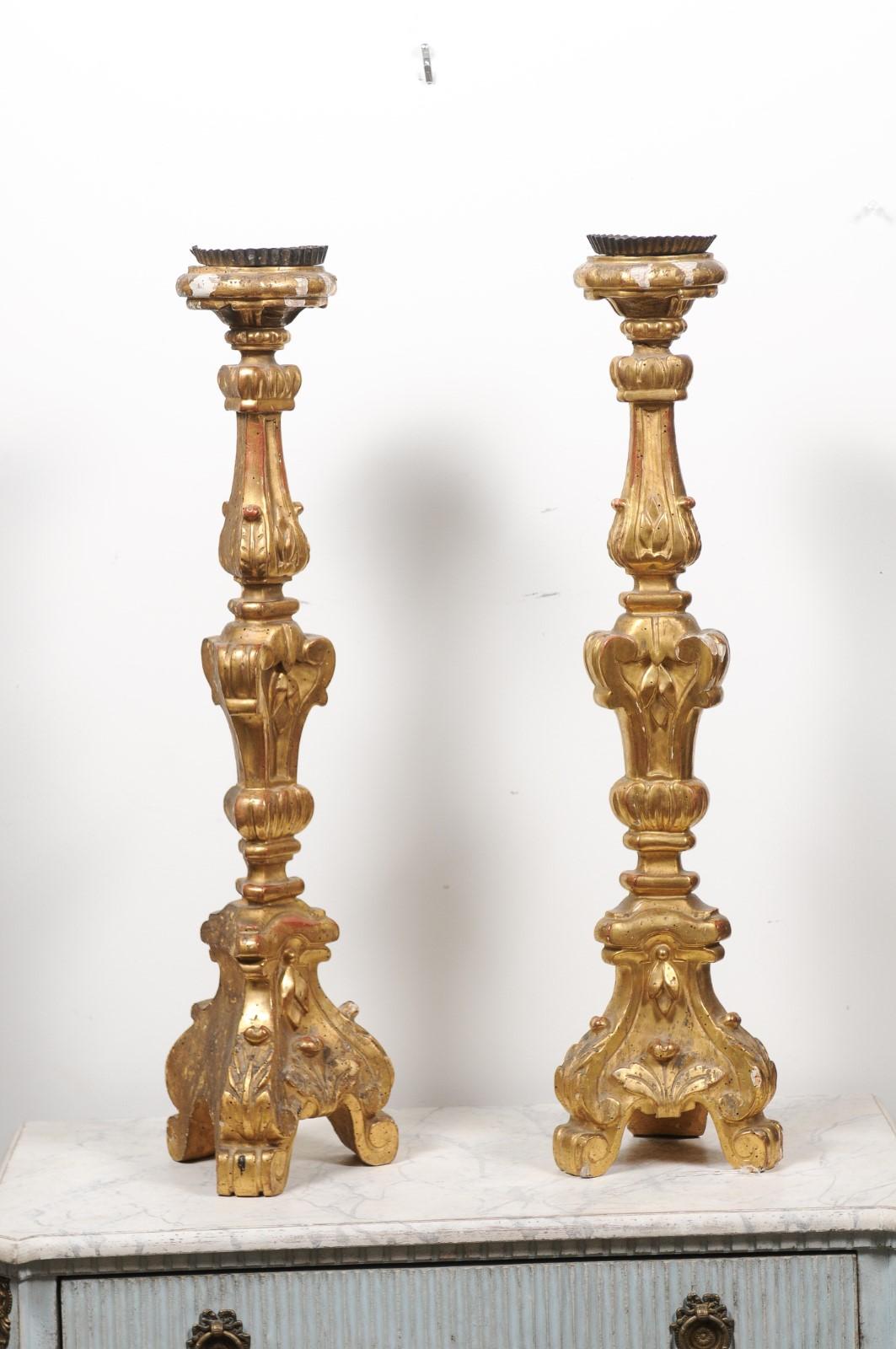 A pair of French giltwood candlesticks from the 19th century, with carved volutes and foliage. Created in France during the 19th century, each of this pair of candlesticks features a delicate décor showcasing foliage and volutes presenting a