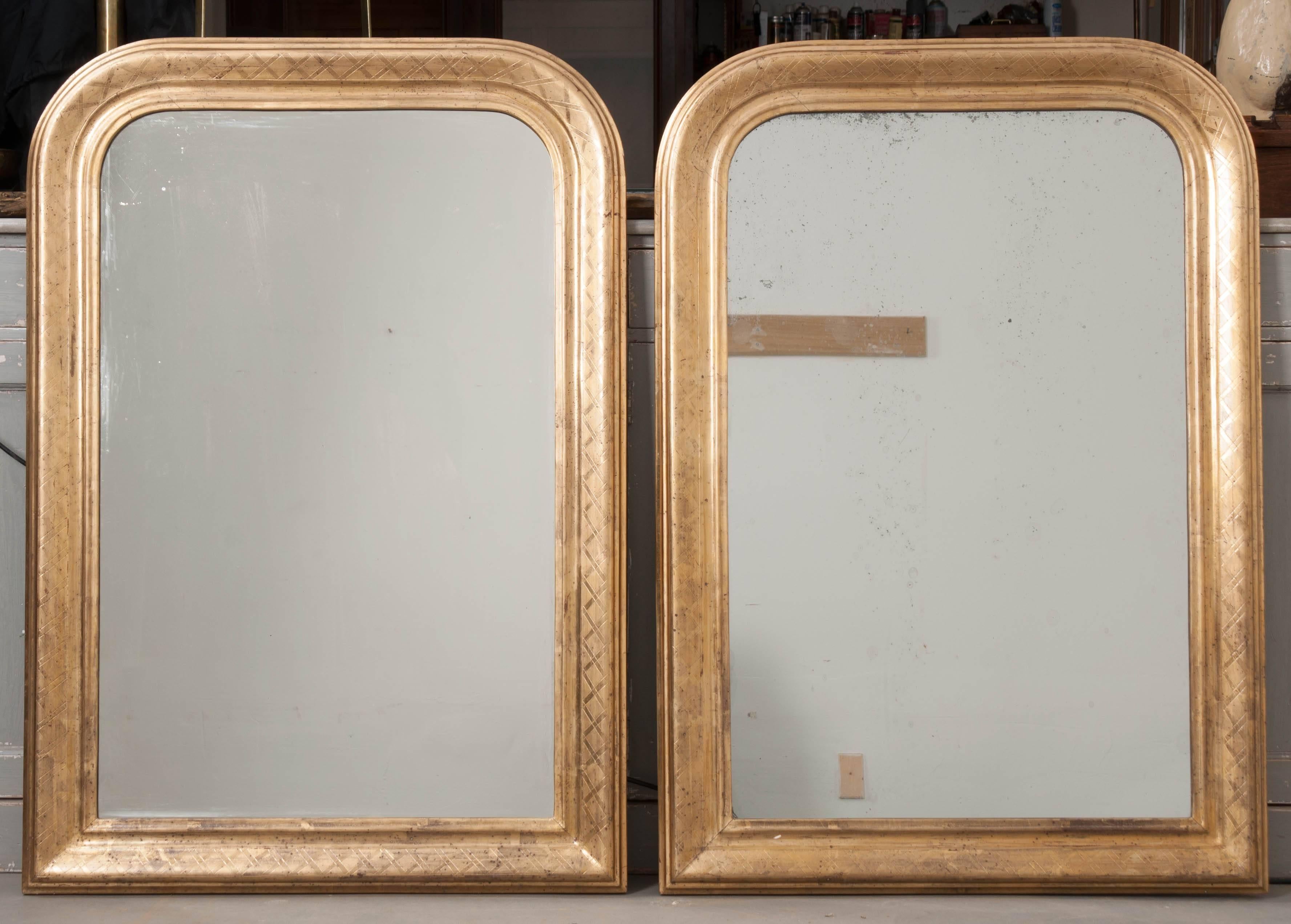 A fabulous pair of gold gilt Louis Philippe mirrors. These 19th century French antique pieces have remarkably intact gold gilt that is brilliant and lustrous. The pair both are finished with an etched cross-hatch design that provides some lovely