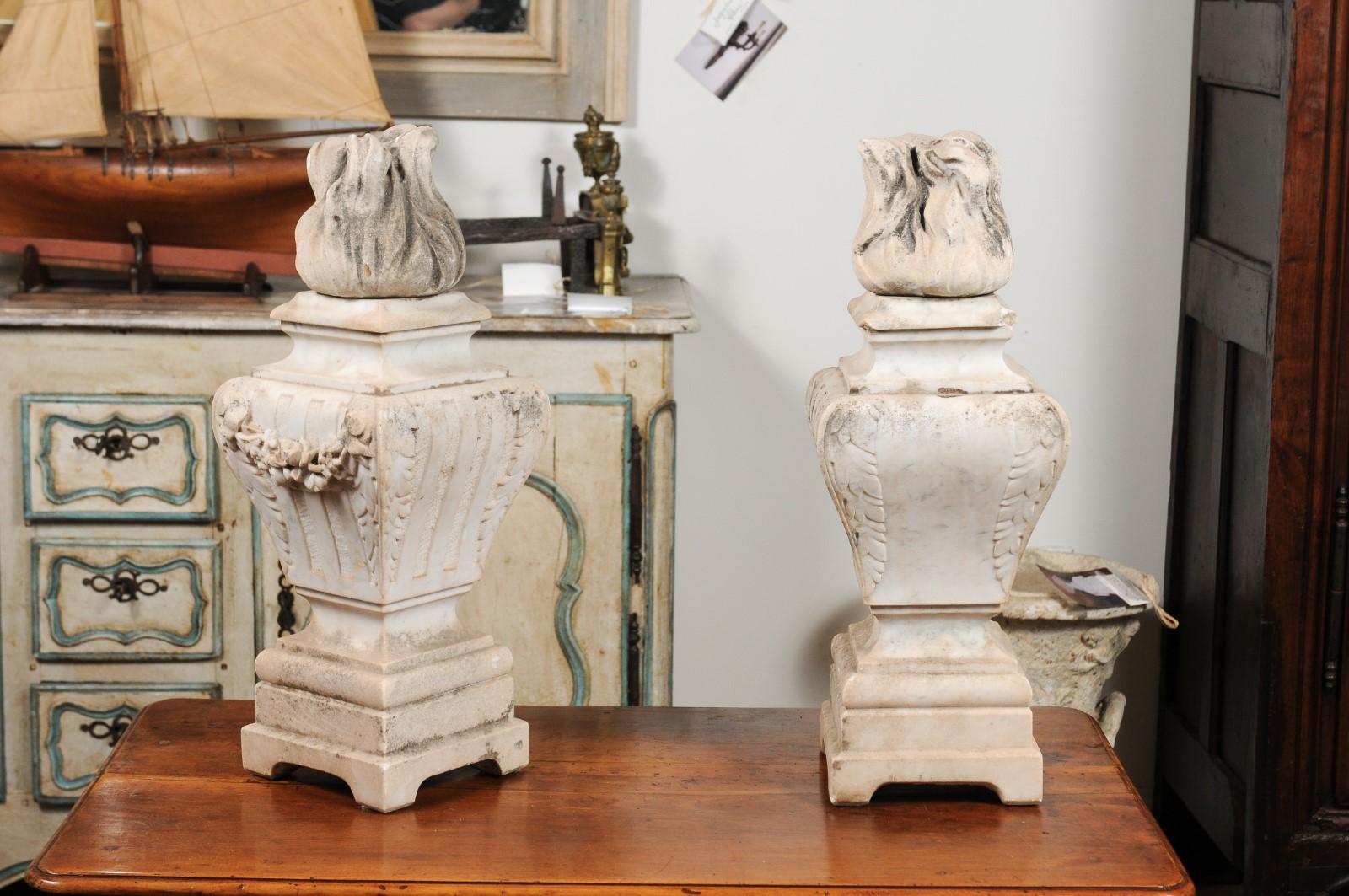 A pair of French hand carved white marble 'Pots à Feu' (fire urns) from the 19th century, with flame, foliage and swag motifs. Born in France during the dynamic 19th century, this pair of pots à feu finds its inspiration in both Baroque and