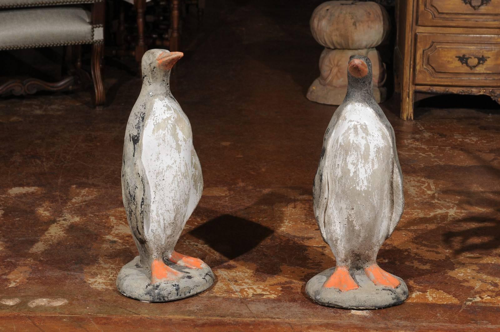 A pair of French lifesize painted stone penguins sculptures from the 19th century on circular bases. Each of this pair of French penguins shows a beautifully weathered appearance, made of white, black and grey tones accented by orange splashes of