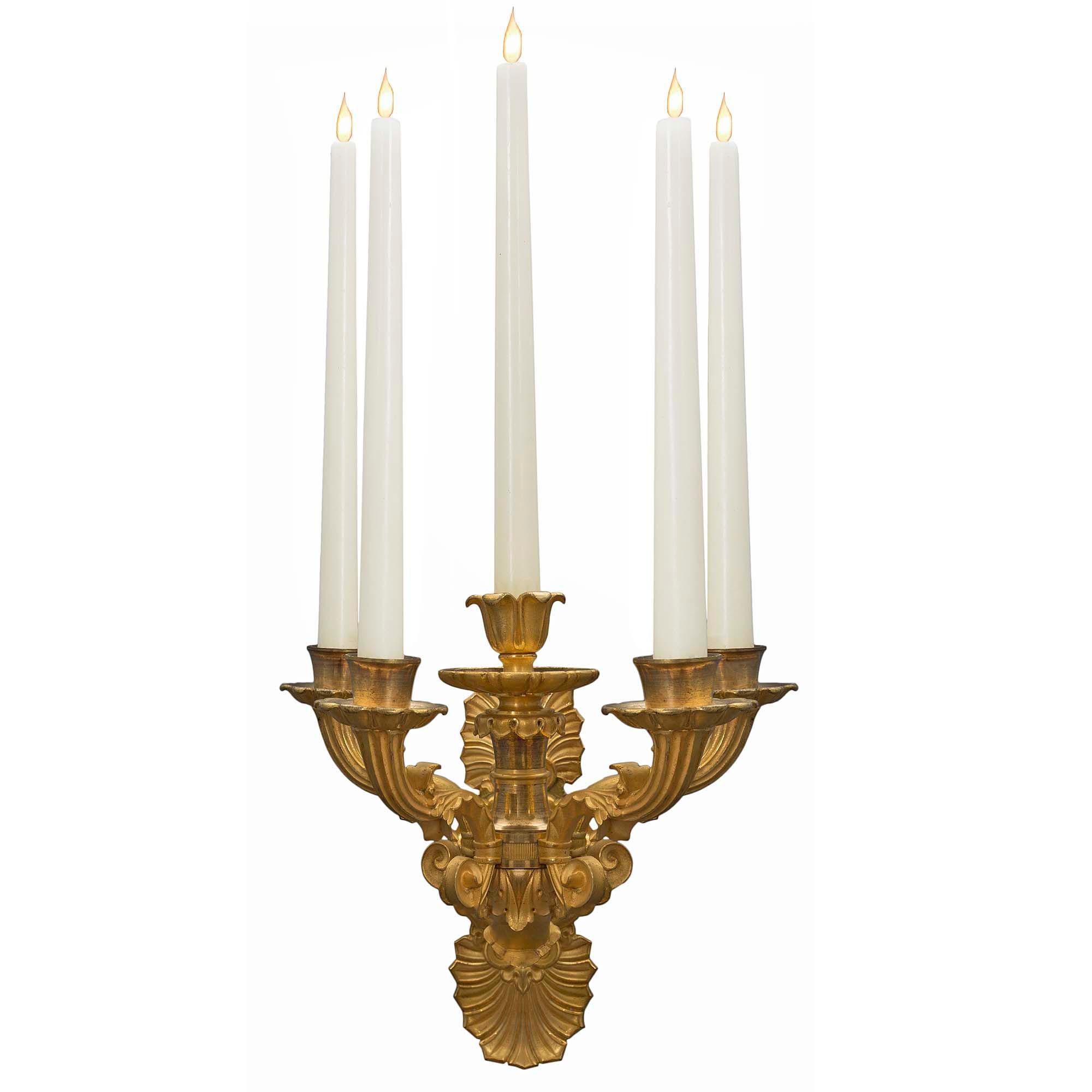 Une belle paire d'appliques à cinq bras de lumière en bronze doré de style Louis Philippe du 19ème siècle. La plaque arrière est ornée d'une coquille festonnée, d'une fleur de lys et d'un motif de volutes en haut et en bas, le tout centré par une