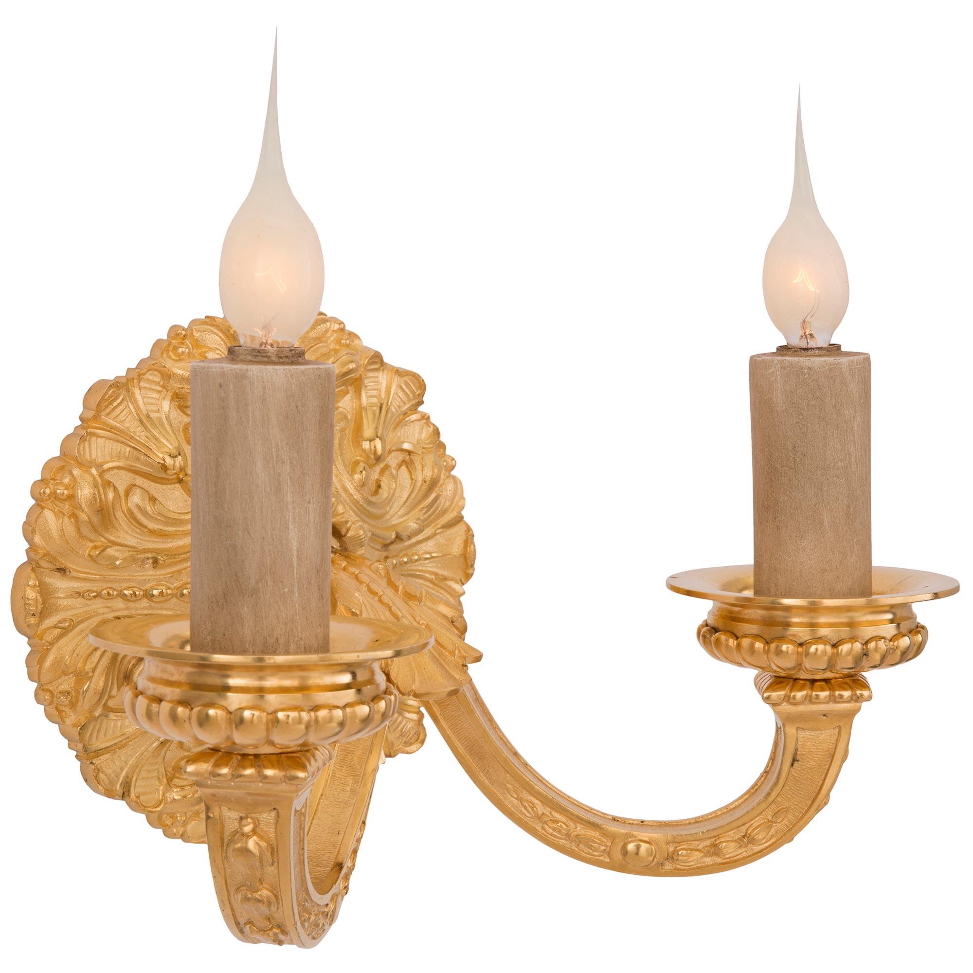 A lovely and most elegant pair of French 19th century Louis XIV st. ormolu sconces, after a model by André-Charles Boulle. Each two arm sconce is centered by a beautiful circular backplate with a finely detailed acanthus leaf design. The two