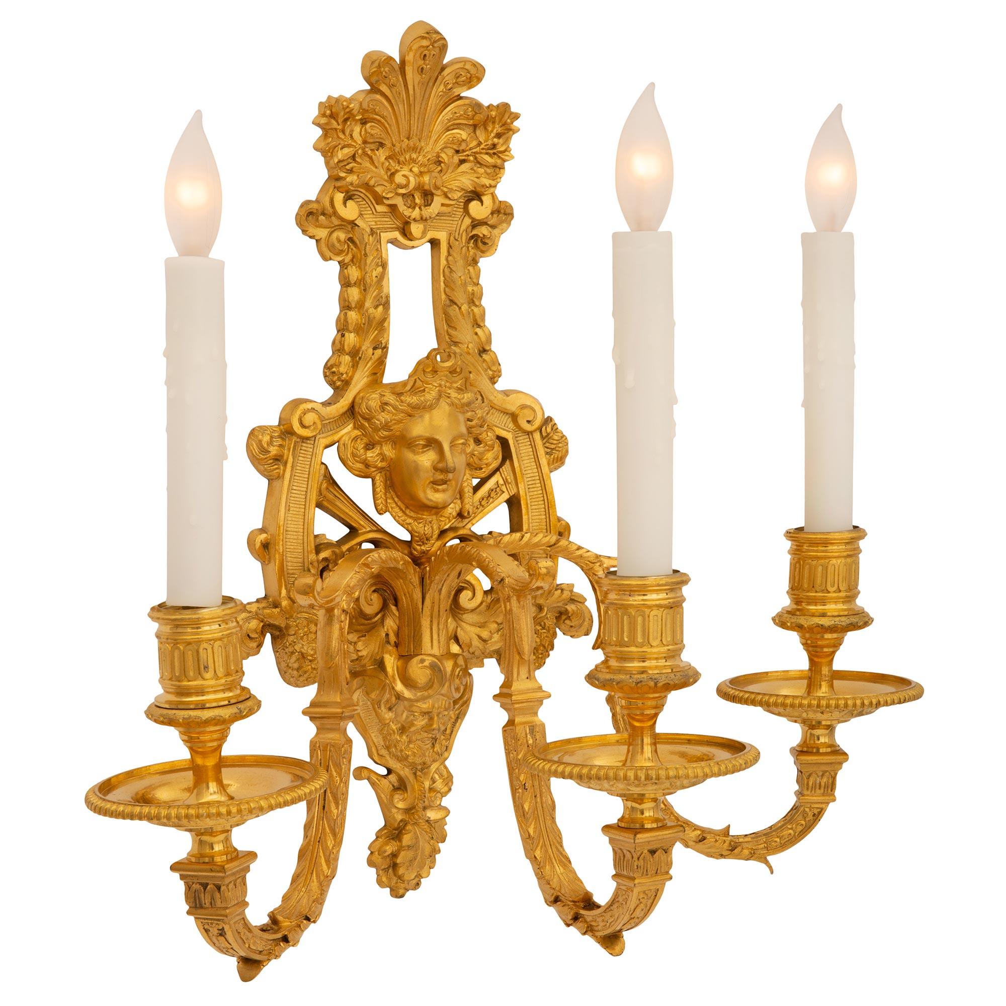 Une belle paire d'appliques françaises du 19ème siècle, de style Louis XIV, en bronze doré. Chaque magnifique applique à trois bras est centrée par une plaque arrière en mosaïque merveilleusement exécutée avec un impressionnant satyre perlé, des