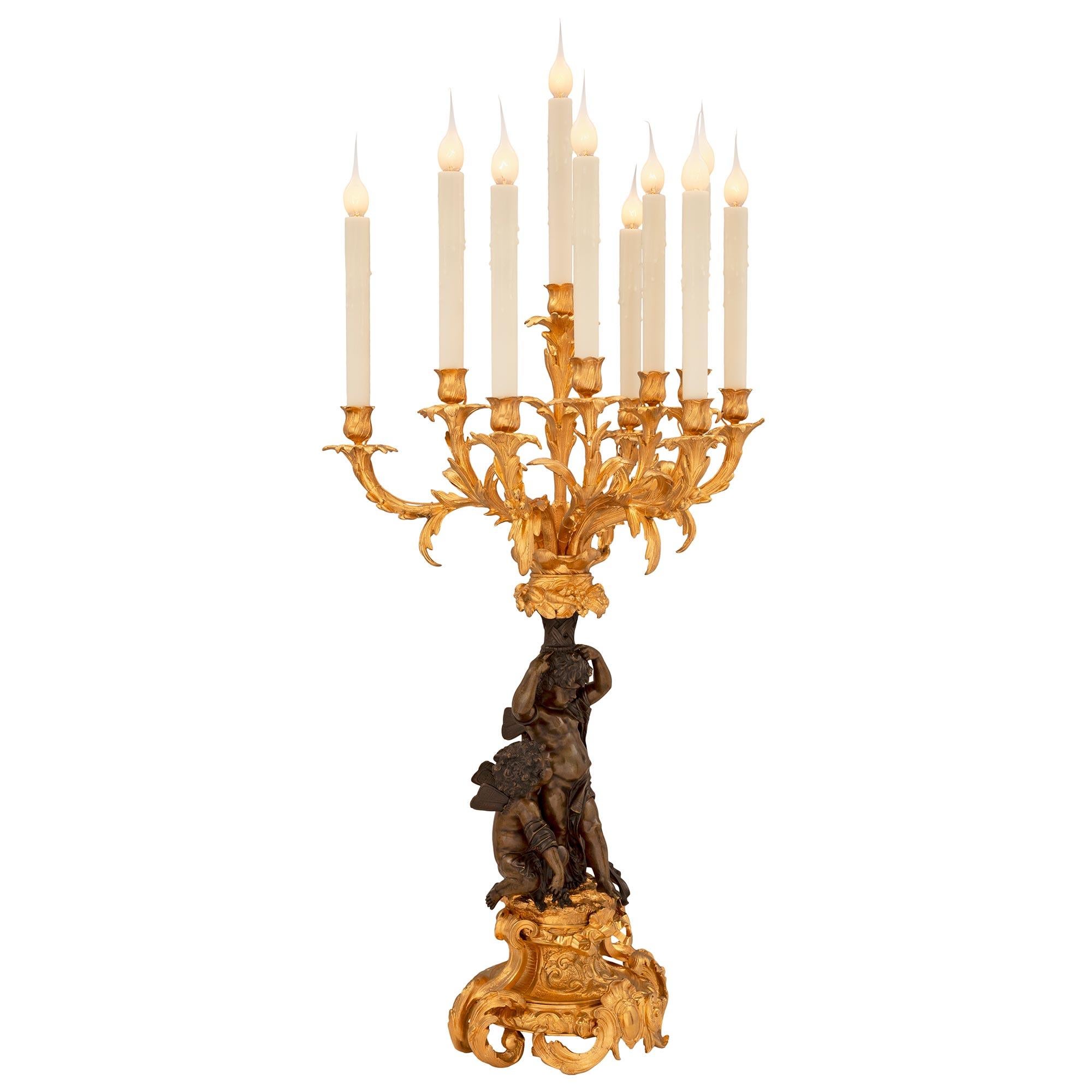 A stunning and most impressive true pair of French 19th century Louis XV st. patinated bronze and ormolu candelabra lamps. Each ten arm lamp is raised by an exceptionally well executed base with beautiful scrolled foliate designs and large acanthus