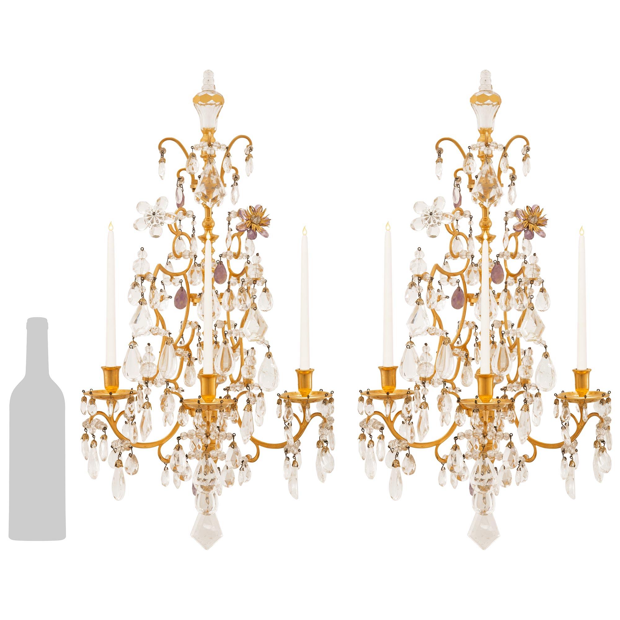 Maravillosa pareja de apliques franceses del siglo XIX de estilo Luis XV de Ormolu, amatista y cristal de roca. Cada impresionante candelabro de tres brazos está centrado por un remate inferior de Ormolu moteado con finos cristales de roca tallados