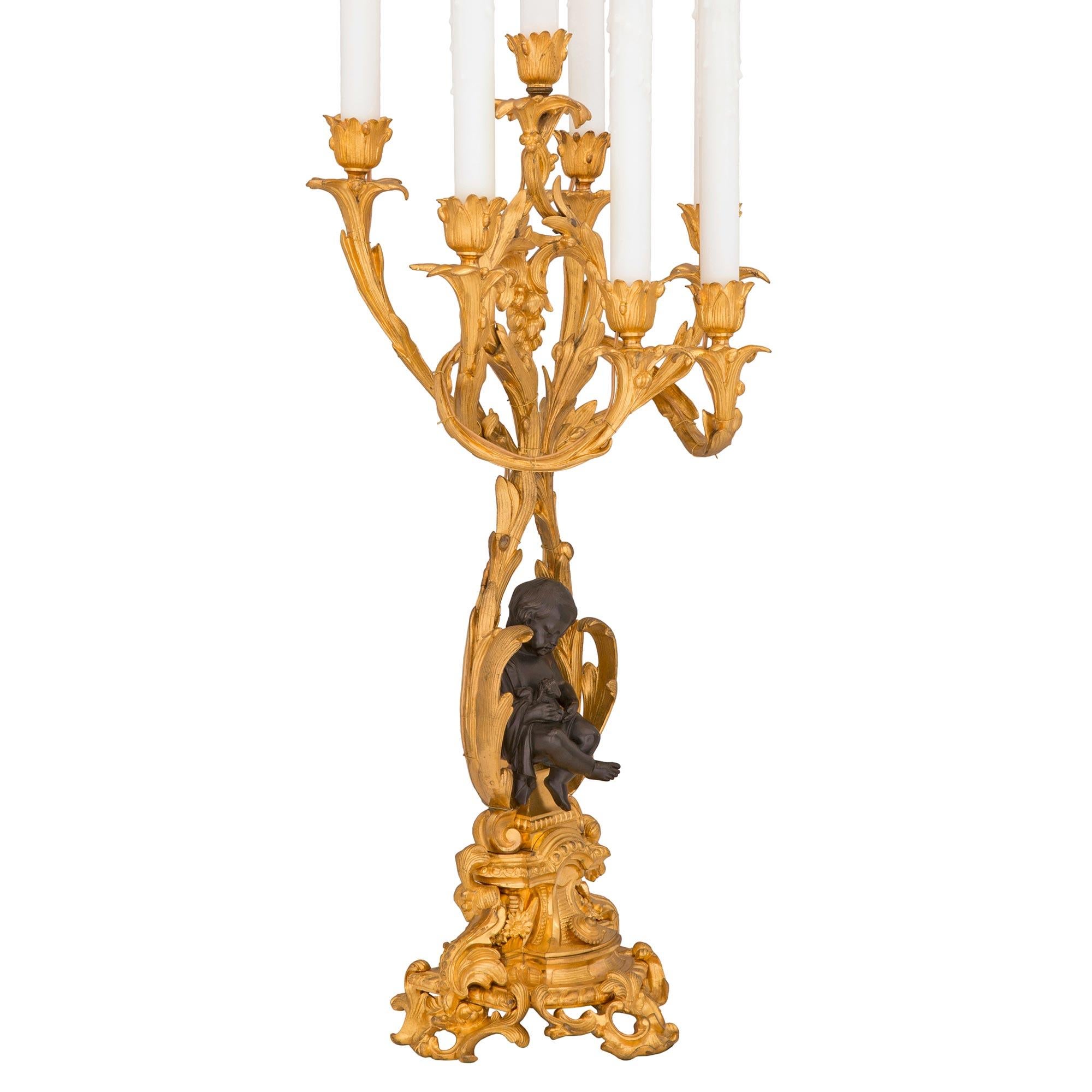 A charming and very high quality pair of French 19th century Louis XV st. ormolu and patinated bronze candelabra lamps. Each seven arm lamp is raised by a beautiful base with striking pierced scrolled foliate movements and a stunning array of most