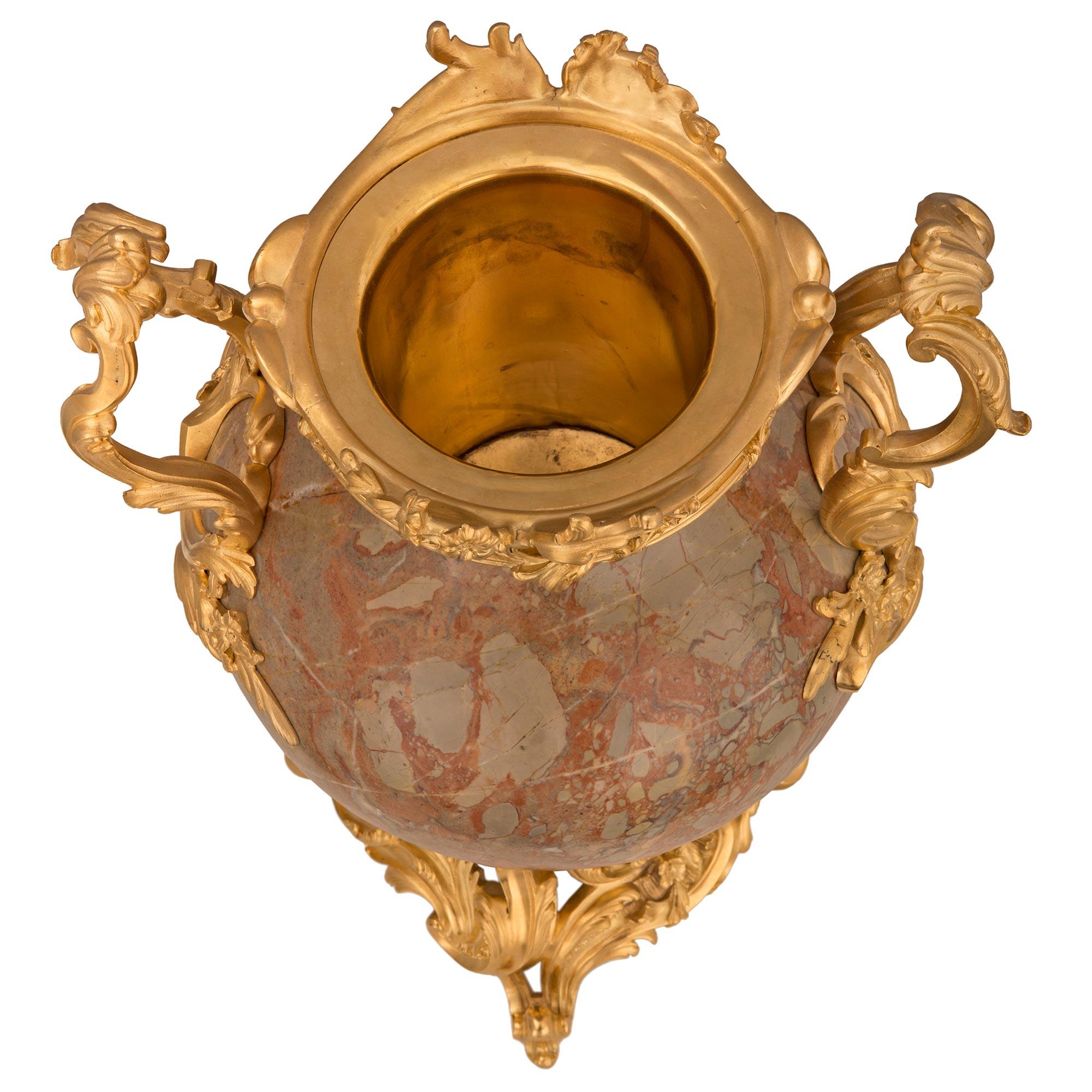A stunning and most impressive pair of French 19th century Louis XV st. ormolu and Sarrancolin marble lidded urns. Each urn is raised by a beautiful pierced ormolu base with exceptional richly chased scrolled foliate movements and charming