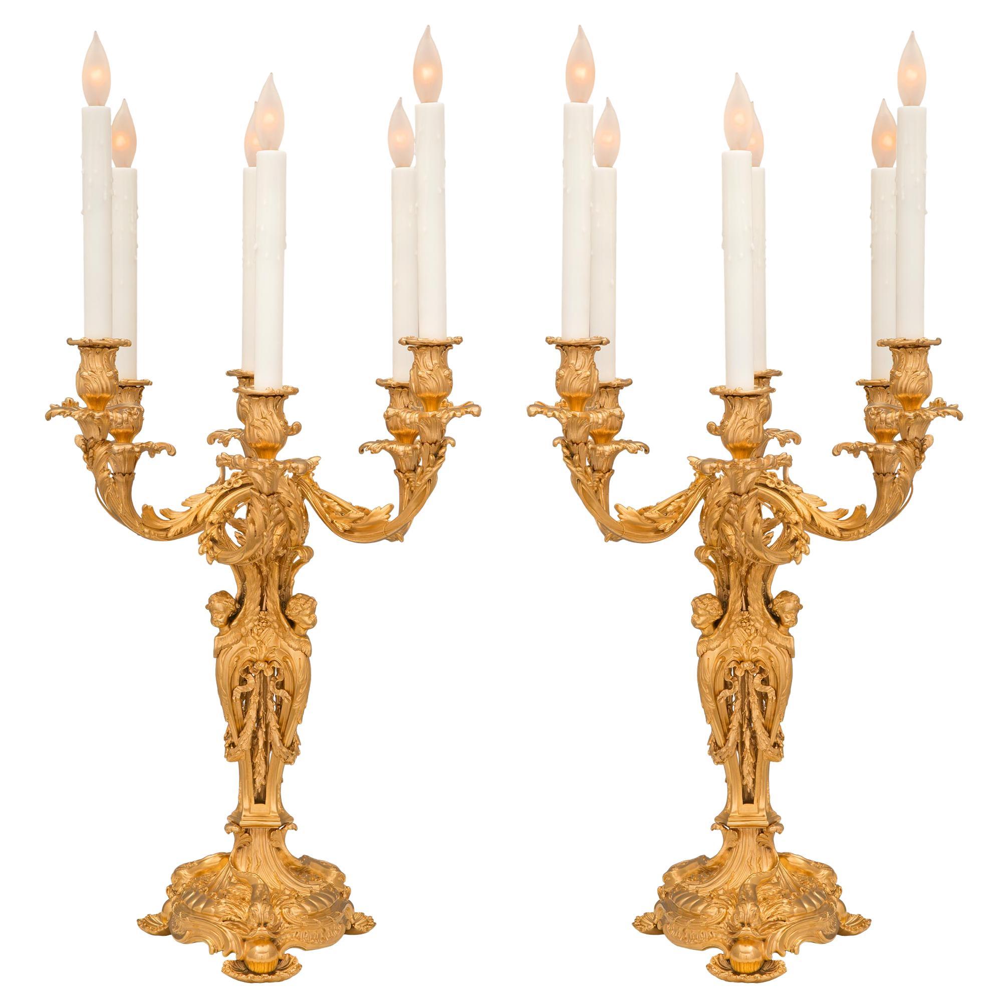 Un par excepcional y de muy alta calidad de lámparas candelabro francesas de ormolina del siglo XIX, estilo Luis XV, atribuidas a François Linke. Cada lámpara de seis brazos se eleva sobre una llamativa base circular foliada maravillosamente