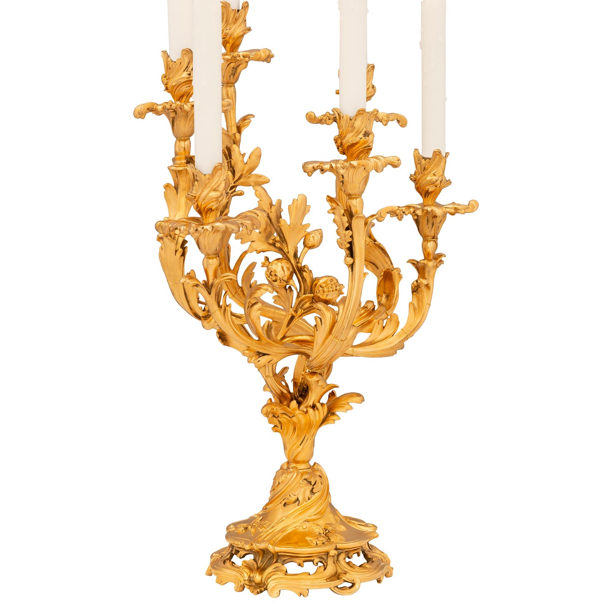Impresionante y elegantísima pareja de candelabros franceses de Ormolu del siglo XIX, estilo Luis XV. Cada candelabro de seis brazos de alta calidad se apoya en una base circular perforada decorada con follaje. Encima hay un zócalo foliado invertido